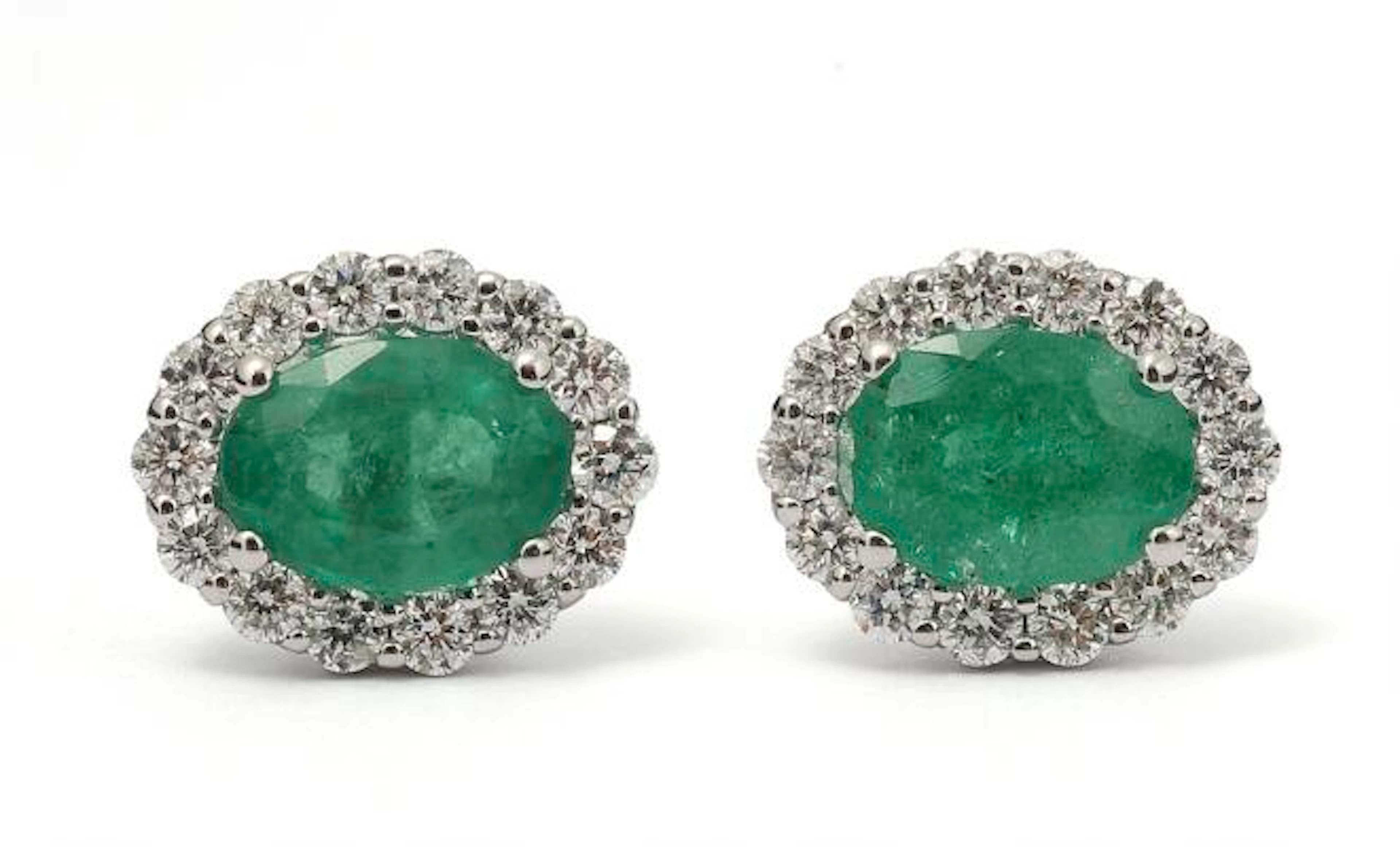 A pair of emerald and diamond ear studs each set with an emerald encircled