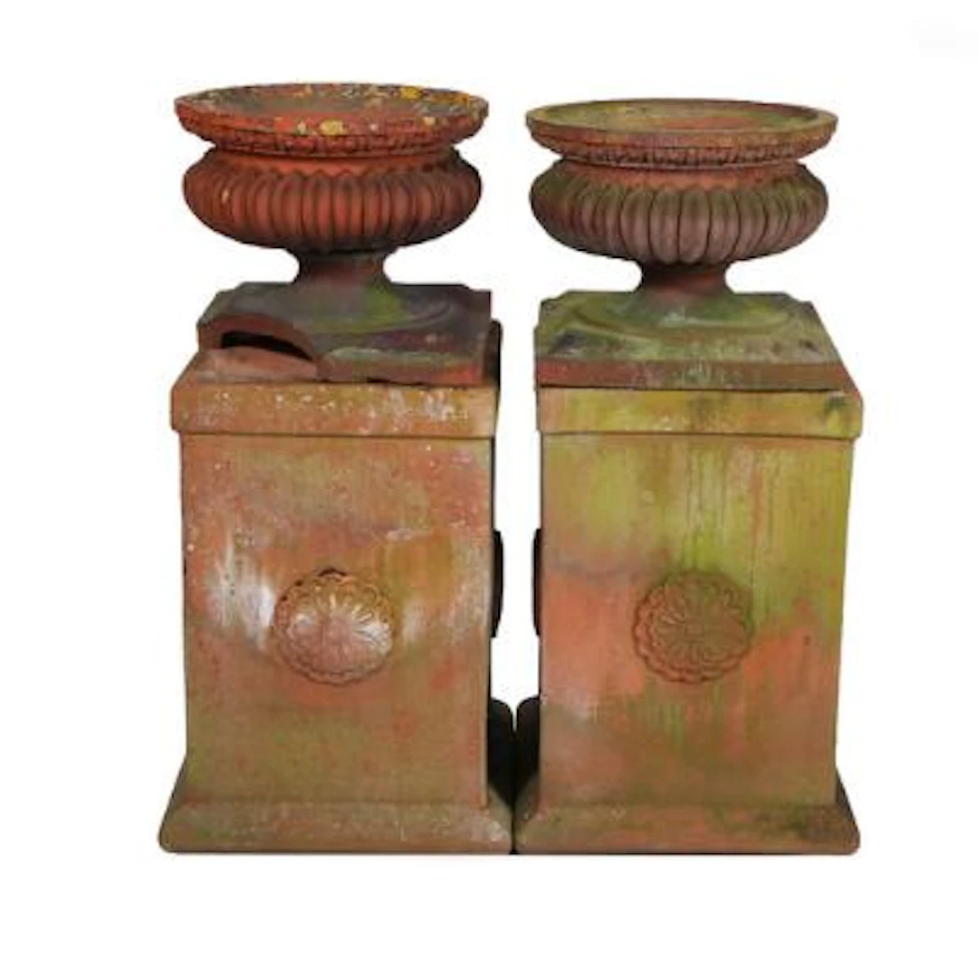 A pair of fluted terracotta garden urns. Raised on four-sided terracotta