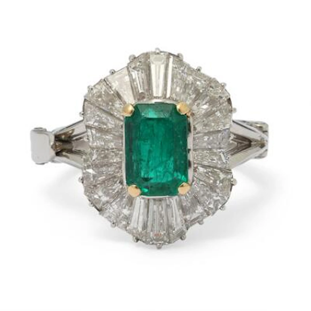 An emerald and diamond ring set with an emerald encircled by diamonds