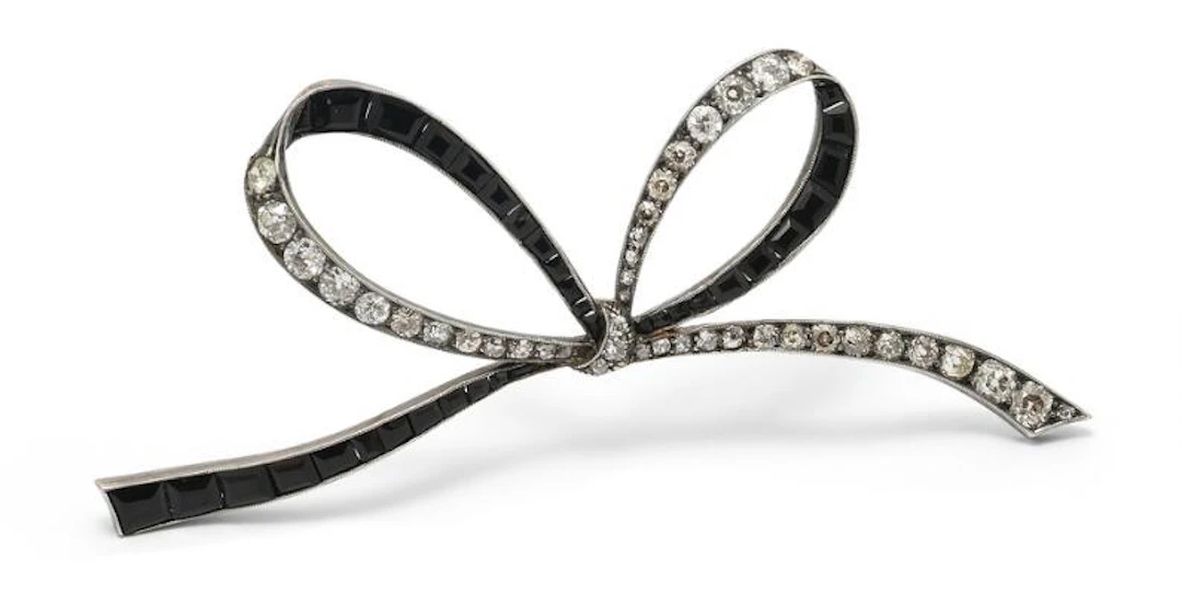 An onyx and diamond brooch of silver and 14k gold in the shape of