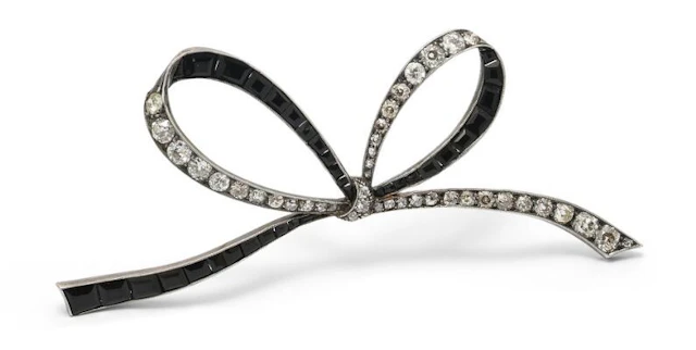 An onyx and diamond brooch of silver and 14k gold in the shape of