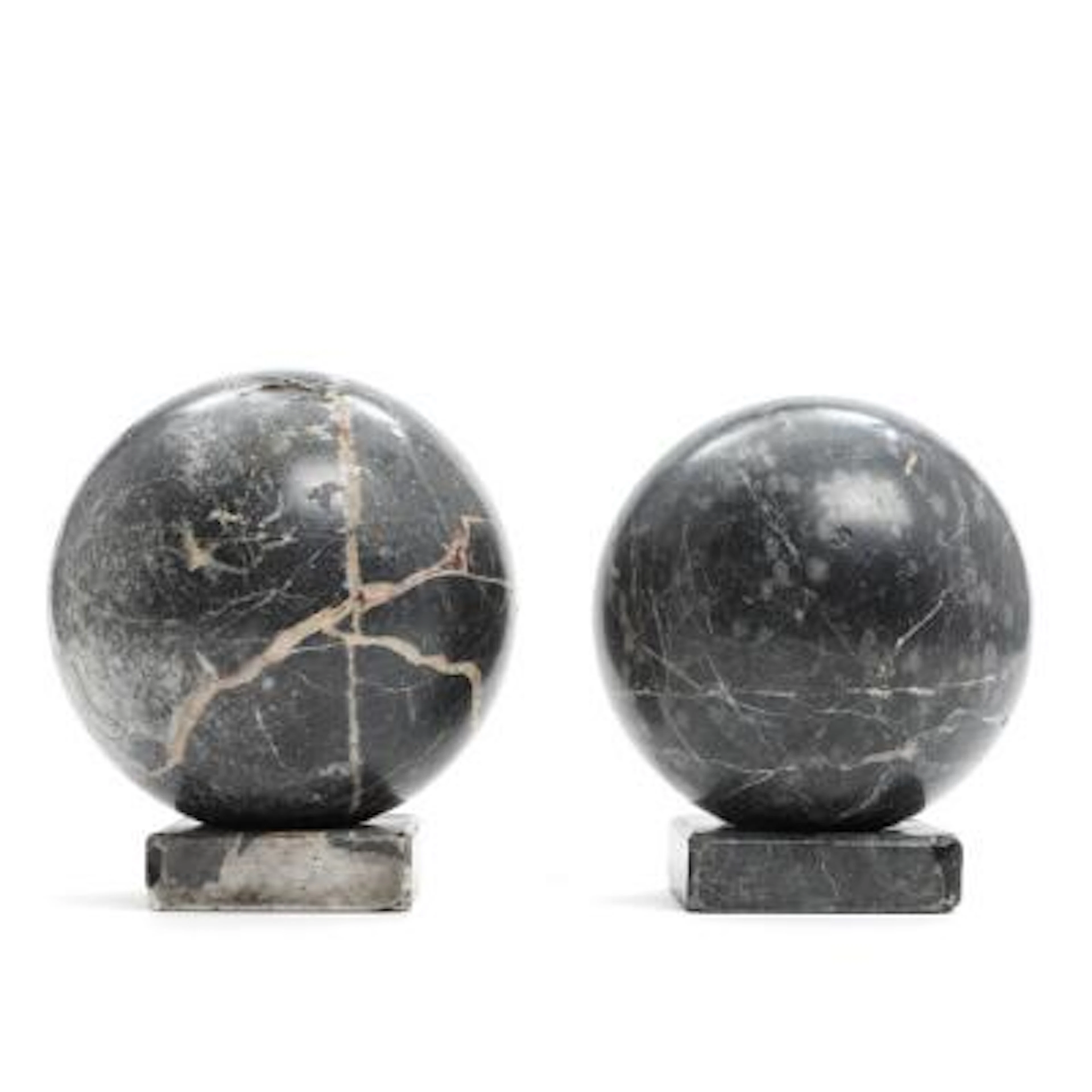 Two decorative spheres of dark-veined marble, on accompanying stands.