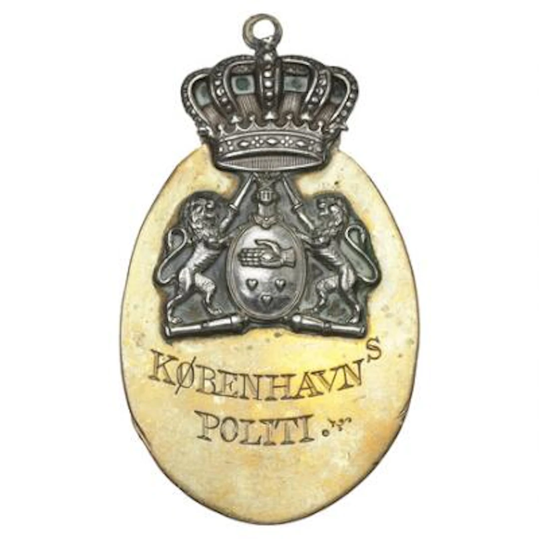 Oval, crowned police badge in brass and light-colored metal from the