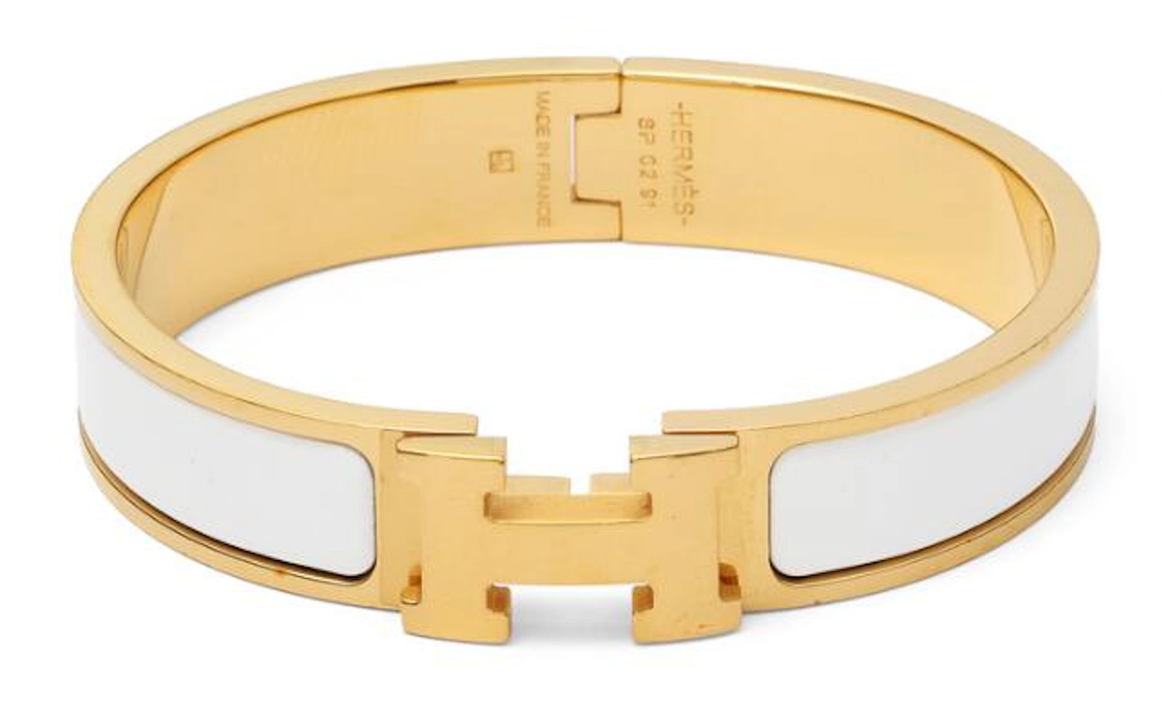 Hermès: A "Clic H" bangle of gilded metal and white enamel. Weight