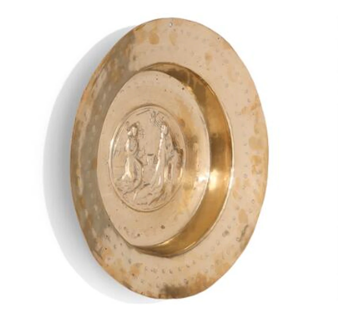 A baptismal basin of embossed and chased brass, The Annunciation.