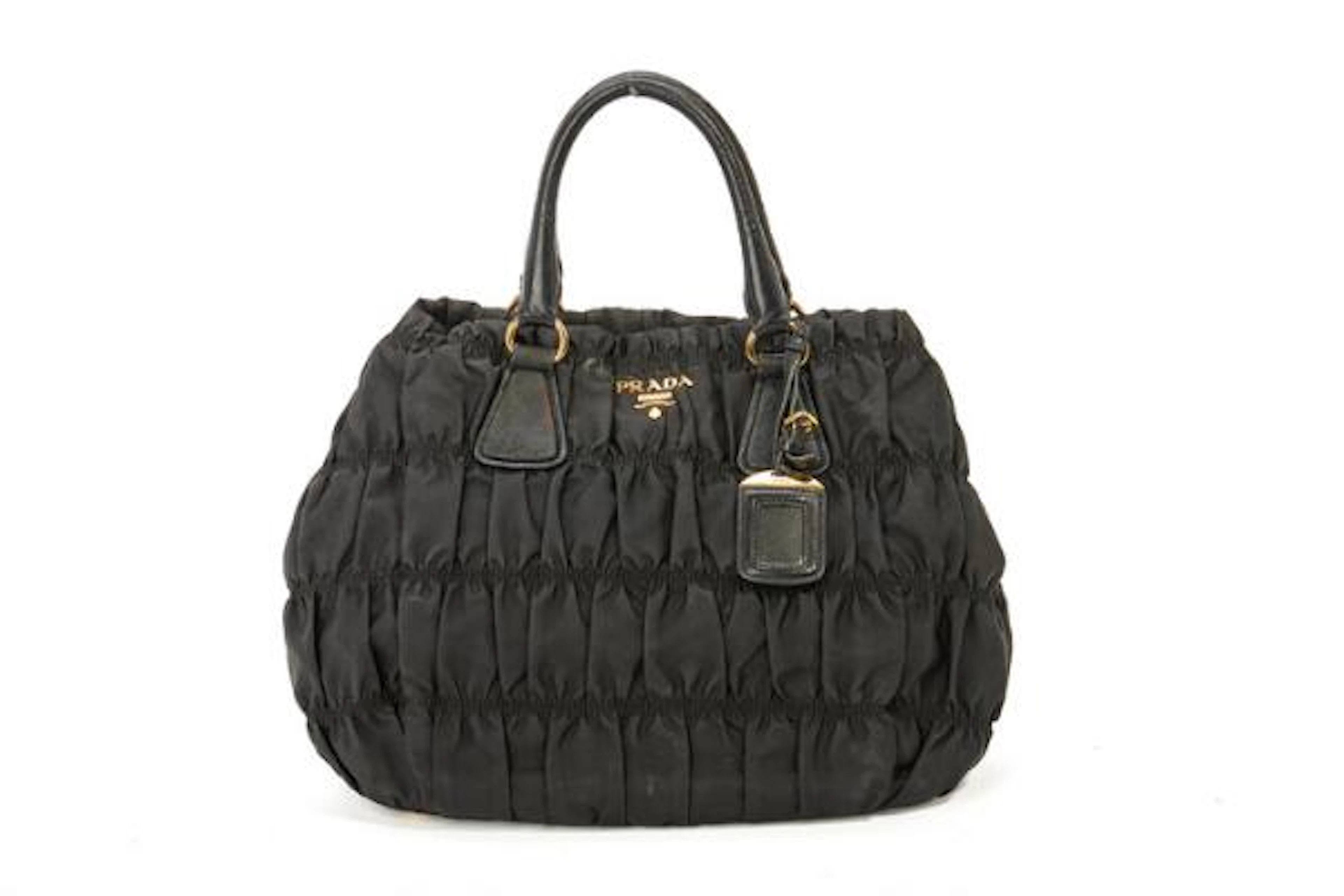 Prada: A bag of black pleated nylon with gold tone hardware, two handles