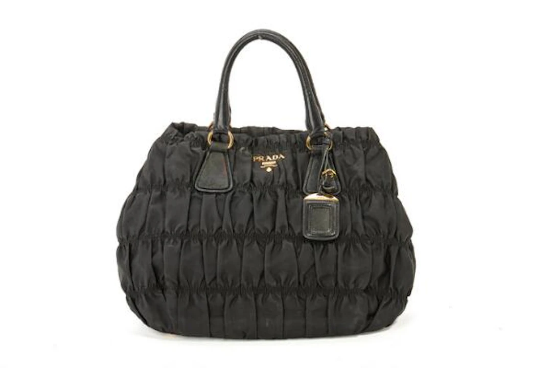 Prada: A bag of black pleated nylon with gold tone hardware, two handles