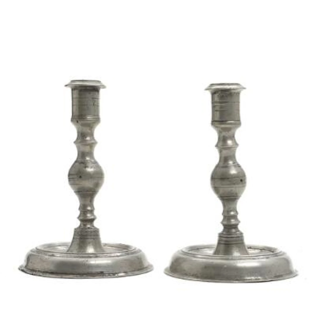 A pair of pewter candlesticks with baluster-form stems on circular