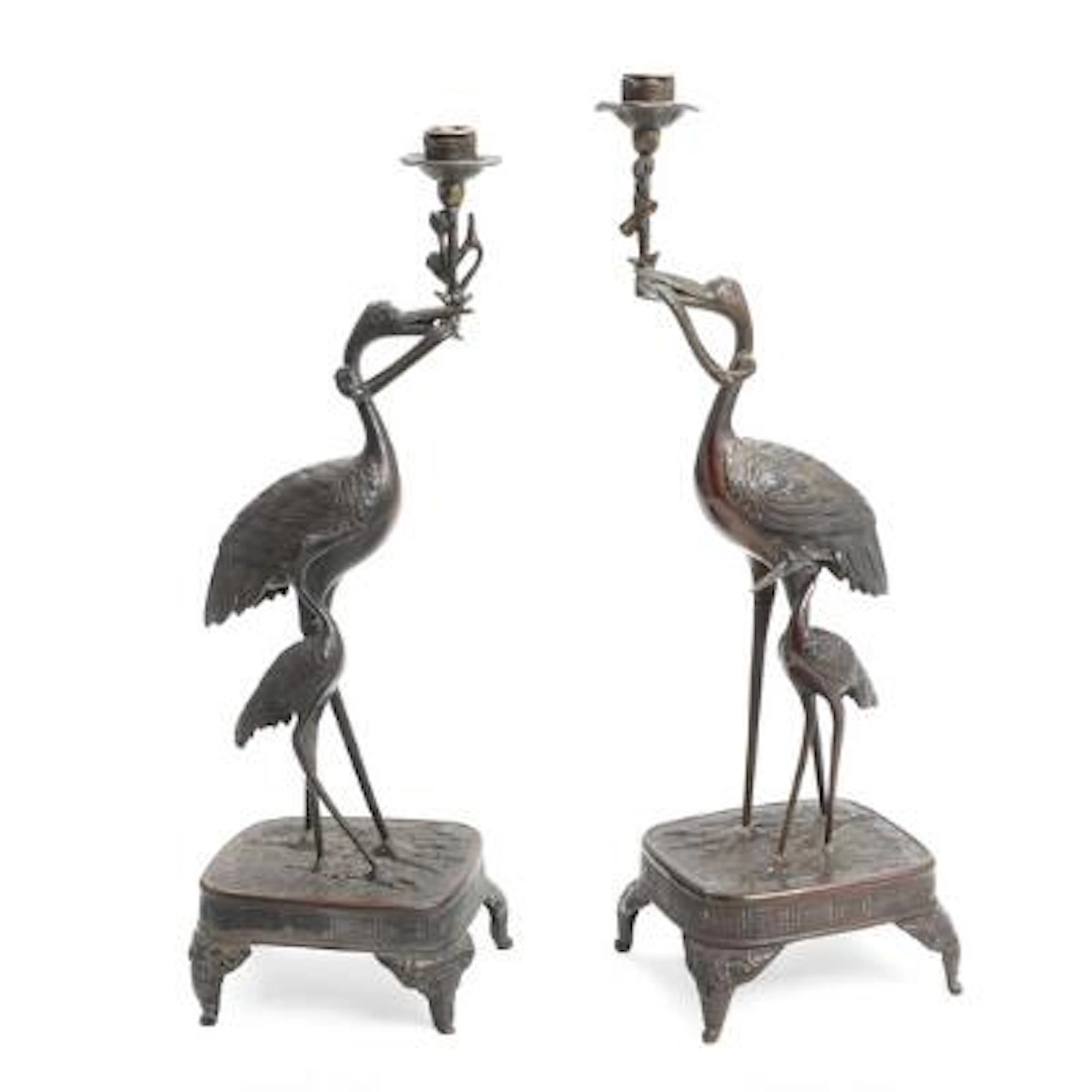 A pair of Japanese patinated bronze candlesticks in the form of cranes.