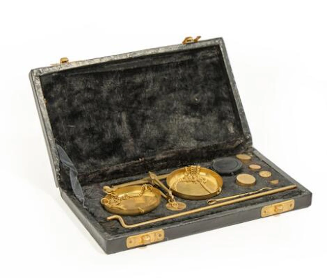 Small travel scale with two weighing pans in gilded metal, weights
