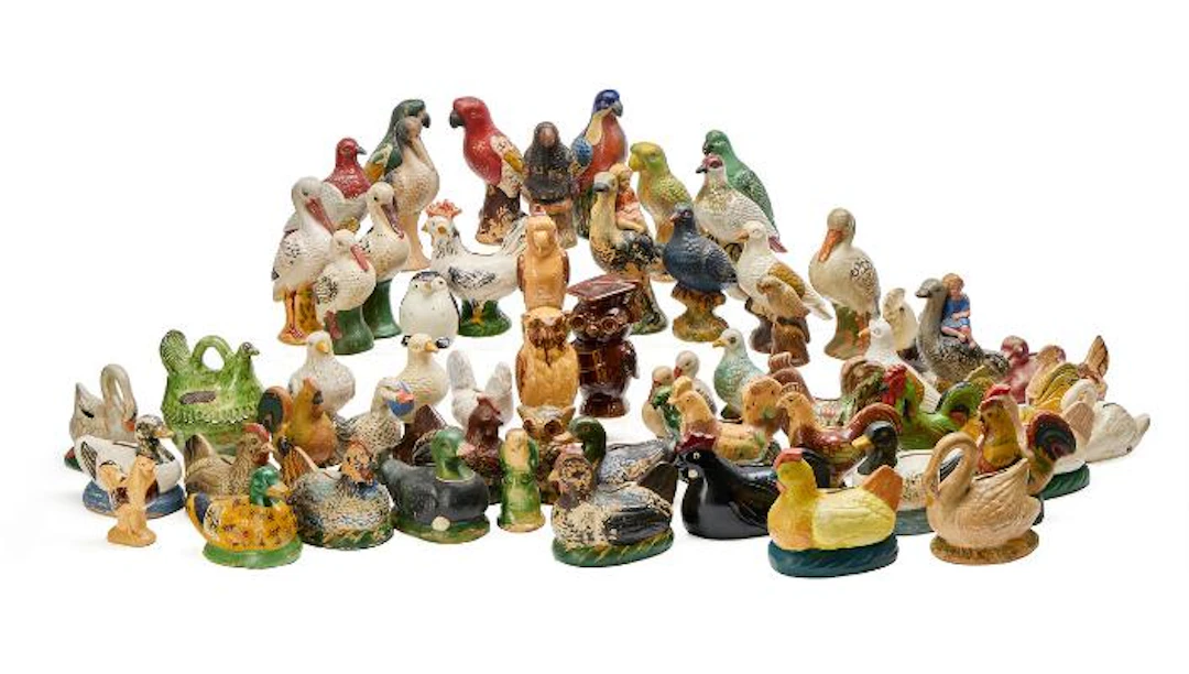 A collection of money boxes in the form of parrots and other birds.