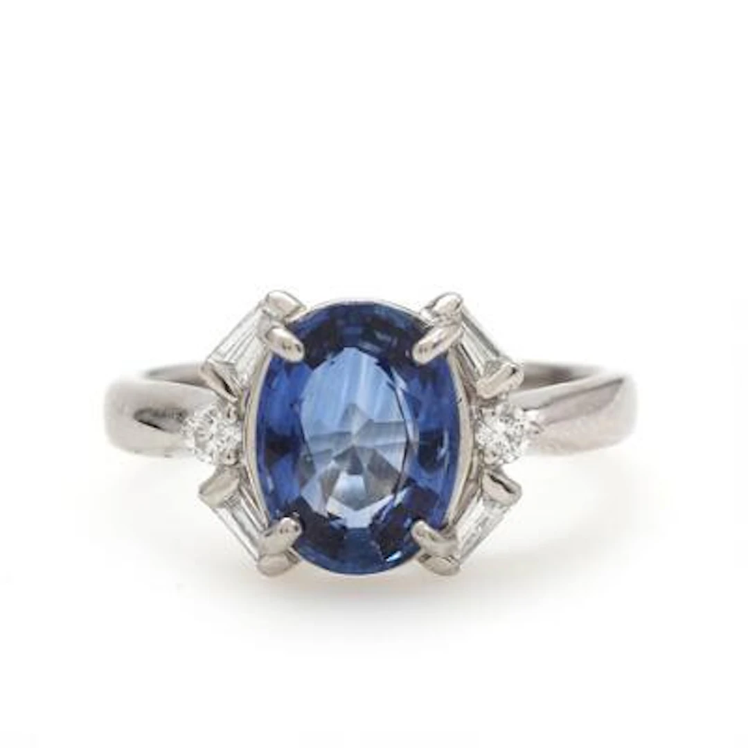 A diamond and sapphire ring set with a faceted sapphire flanked by