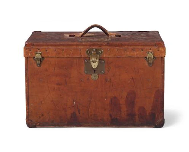 Louis Vuitton: A vintage travel trunk of dark wood with brass hardware.
