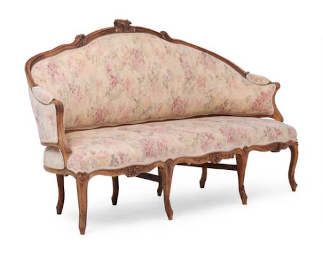 A French rococo walnut sofa with curved back sides and seat carved