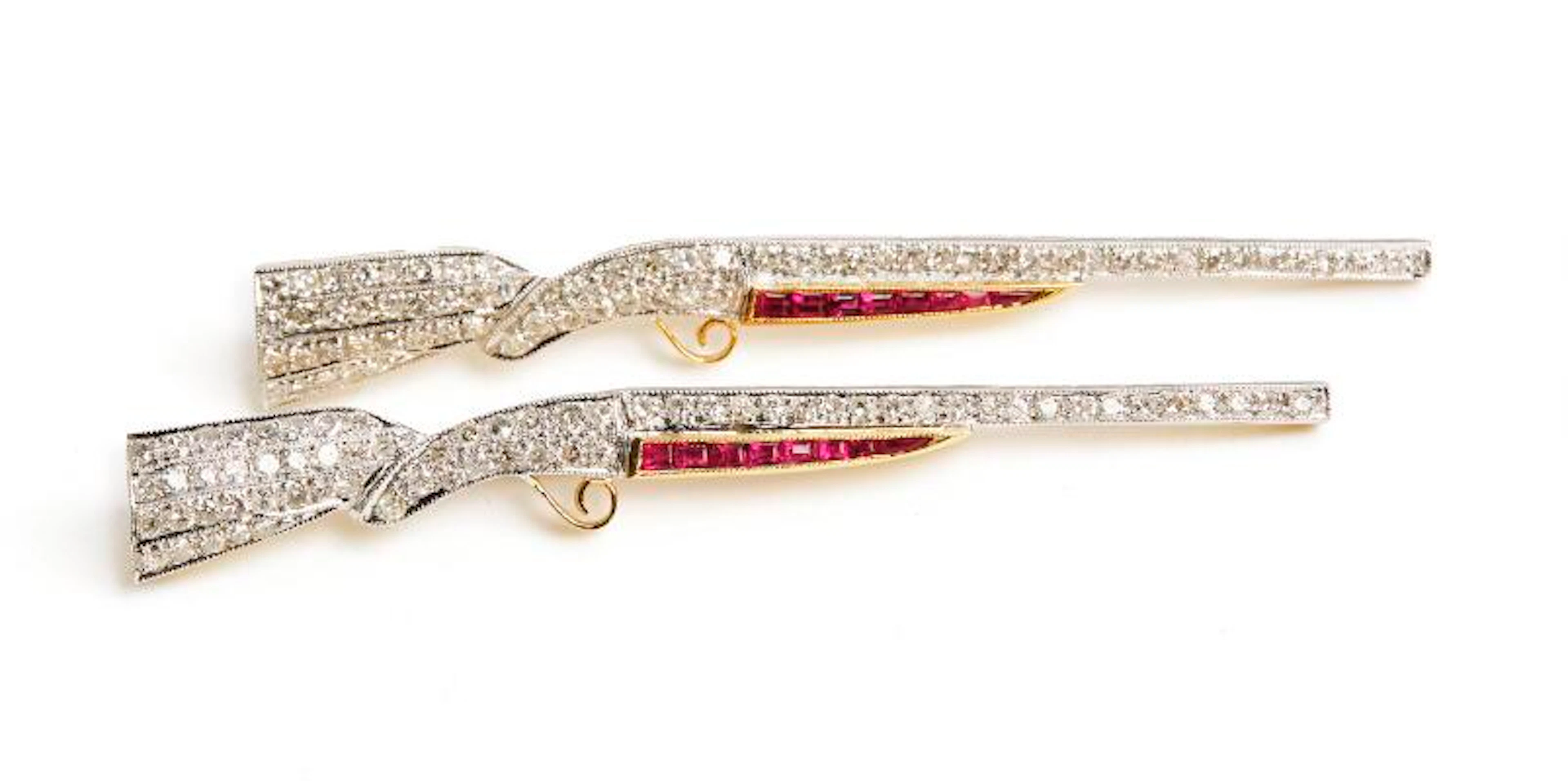 A pair of brooches in the shape of riffles each set with diamonds