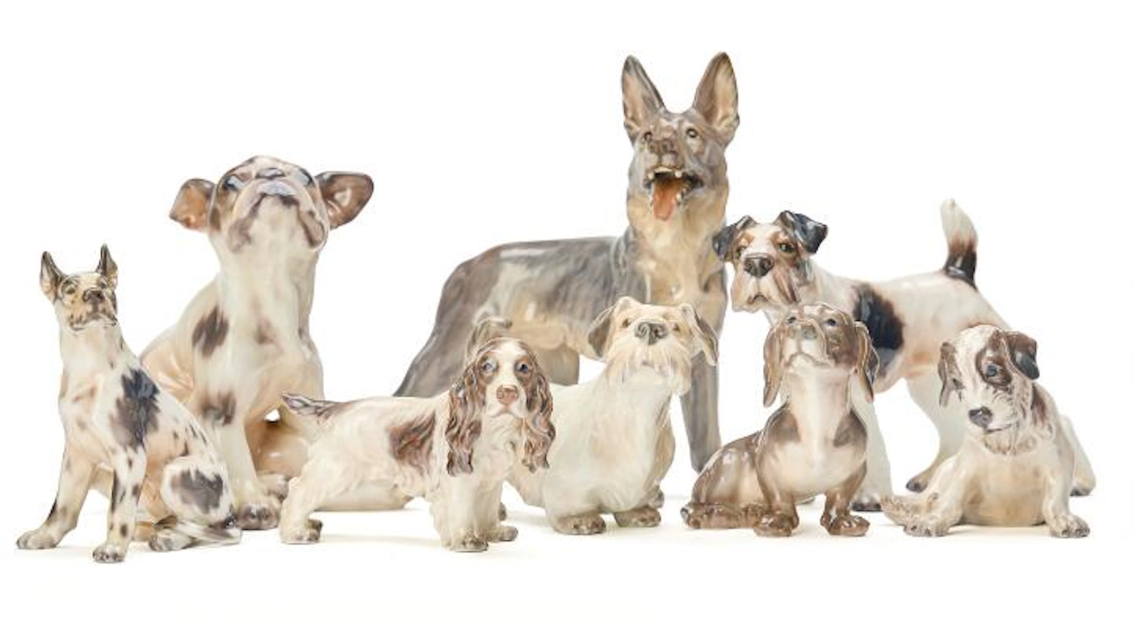 Eight various porcelain dogs decorated in underglaze colours. Dahl-Jensen.