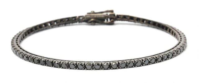 A diamond bracelet set with numerous black diamonds, mounted in 14k