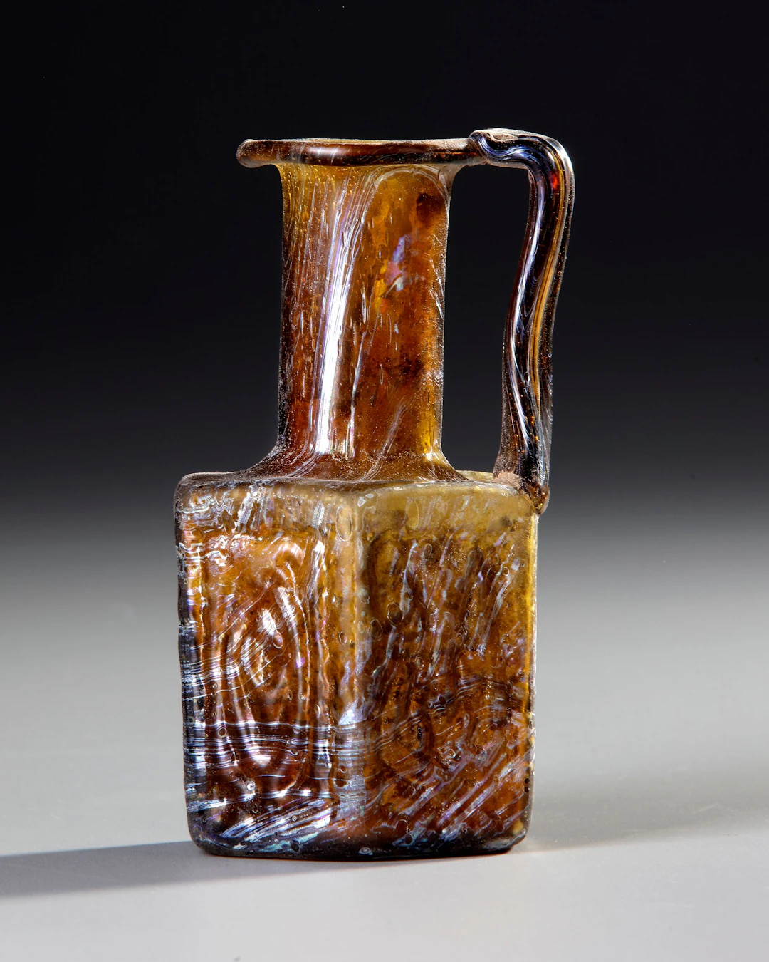AN AMBER MOLDED GLASS JUGLET, EASTERN MEDITERRANEAN, 1ST–3RD CENTURY AD