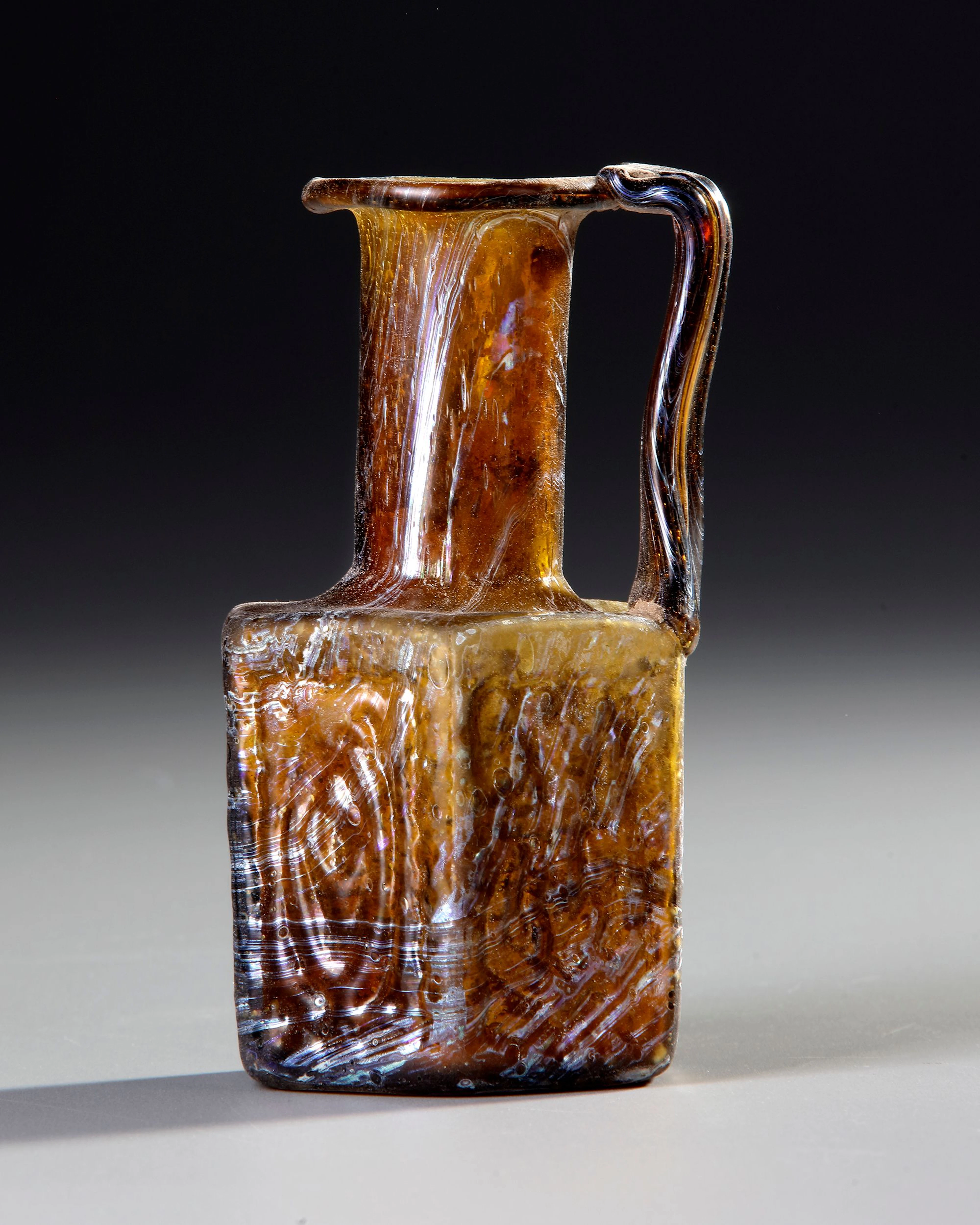 AN AMBER MOLDED GLASS JUGLET, EASTERN MEDITERRANEAN, 1ST–3RD CENTURY AD