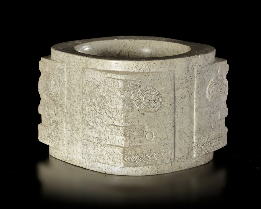 A BEIGE-COLORED JADE CONG WITH RUST-LIKE BROWN INCLUSIONS DECORATED