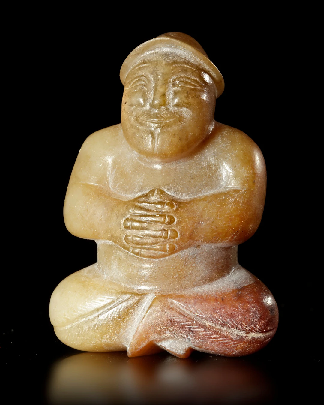 A BEIGE BROWN JADE CROSS LEGGED MALE FIGURE, CHINA, EASTER HAN DYNASTY