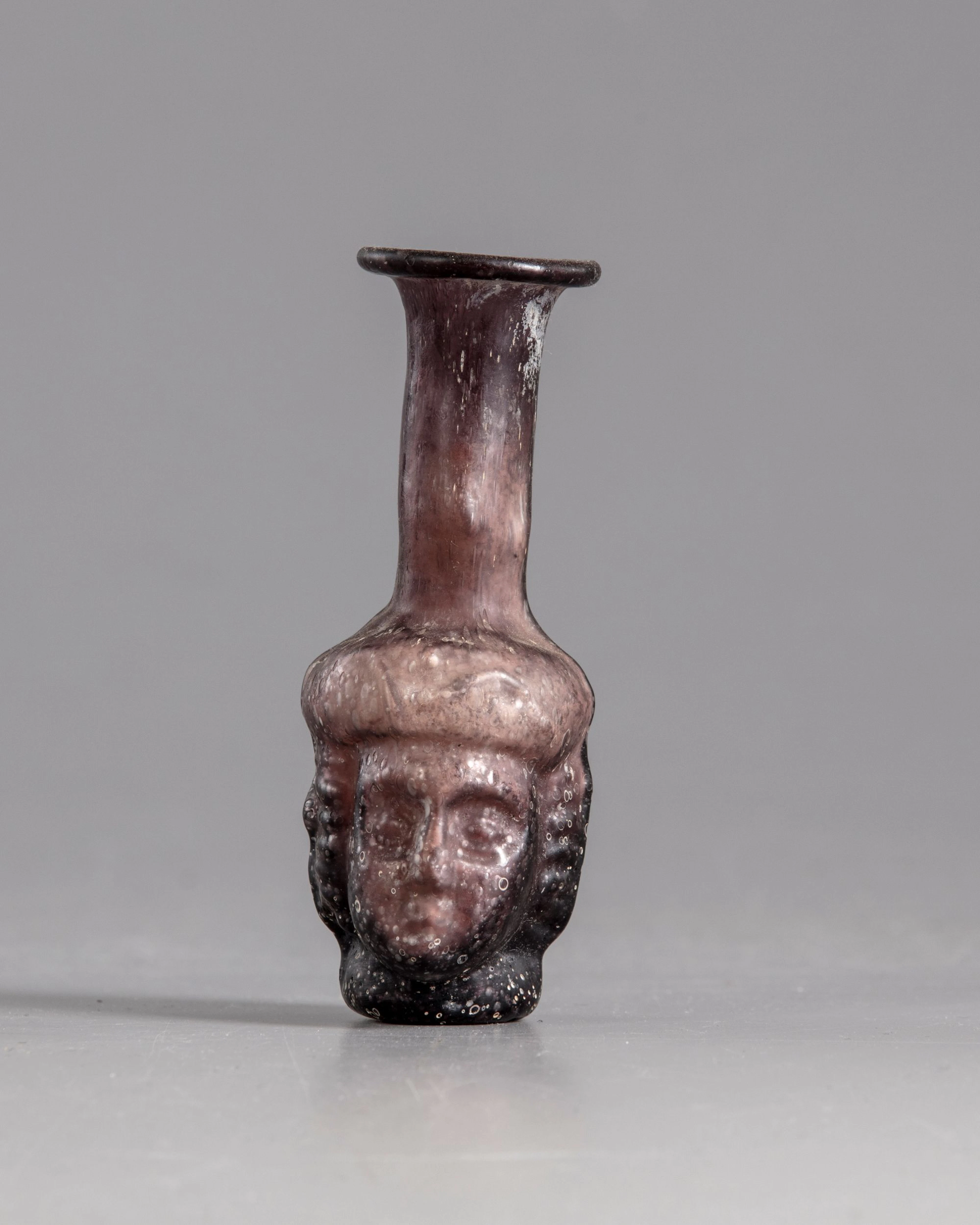 A ROMAN GLASS HEAD FLASK, CIRCA 3RD CENTURY AD