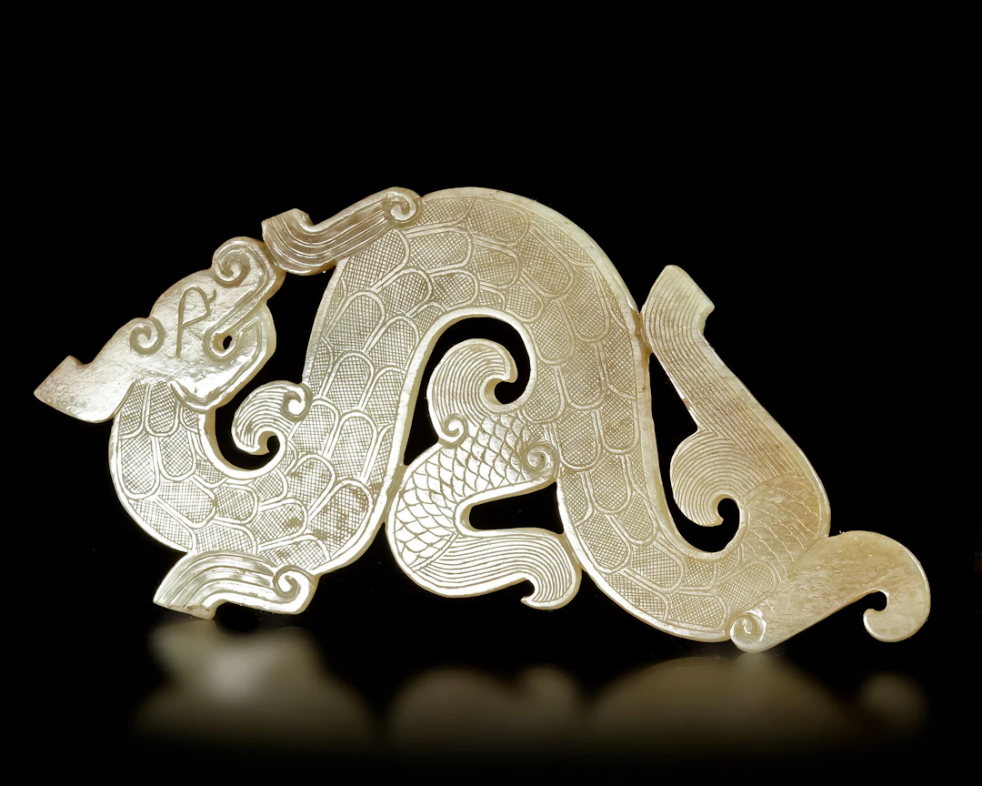 A LIGHT GREEN JADE 'S' DRAGON PENDANT, CHINA, HAN DYNASTY (206 BC-220 AD)