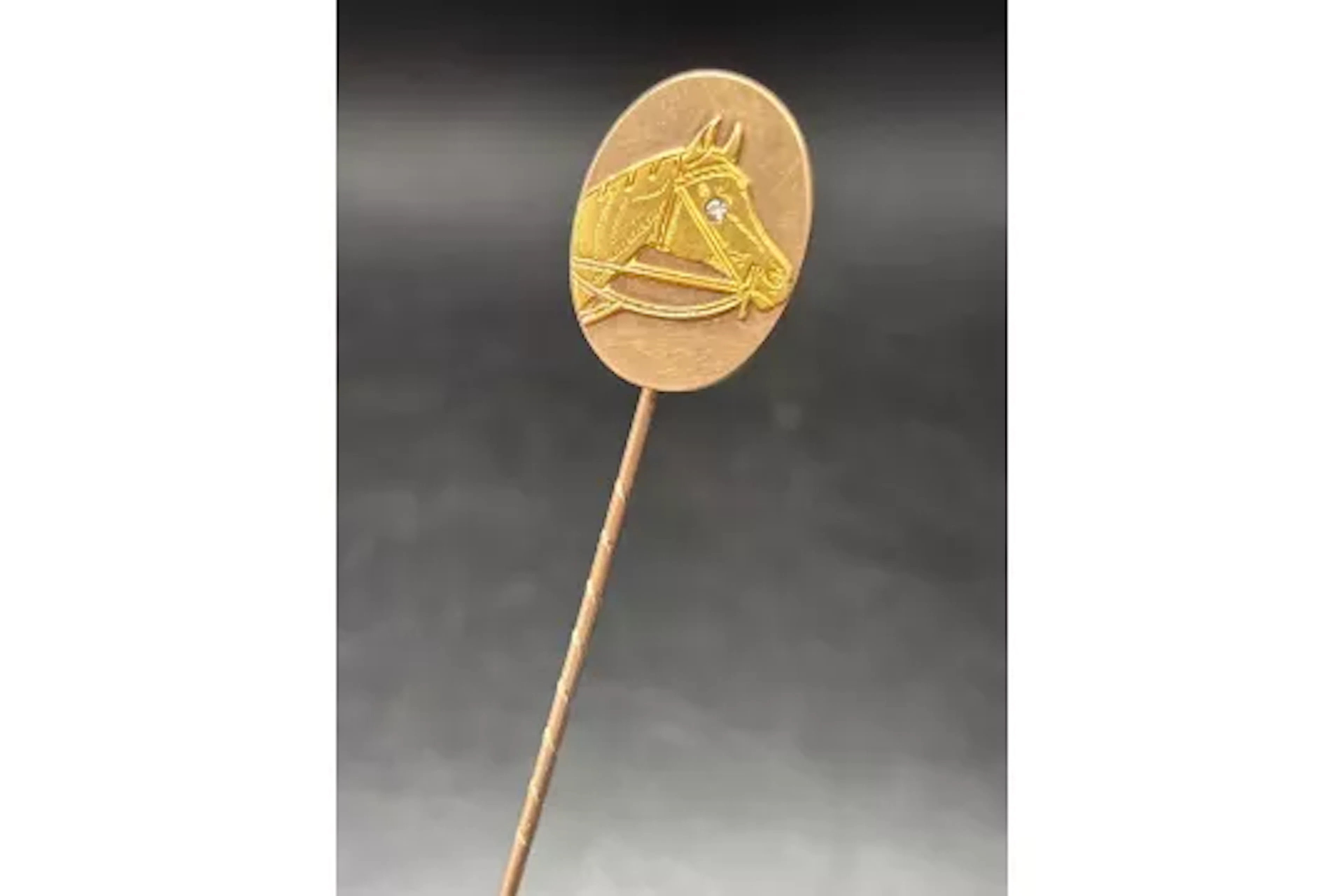 A good yellow metal horse head stick pin with white stone eye
