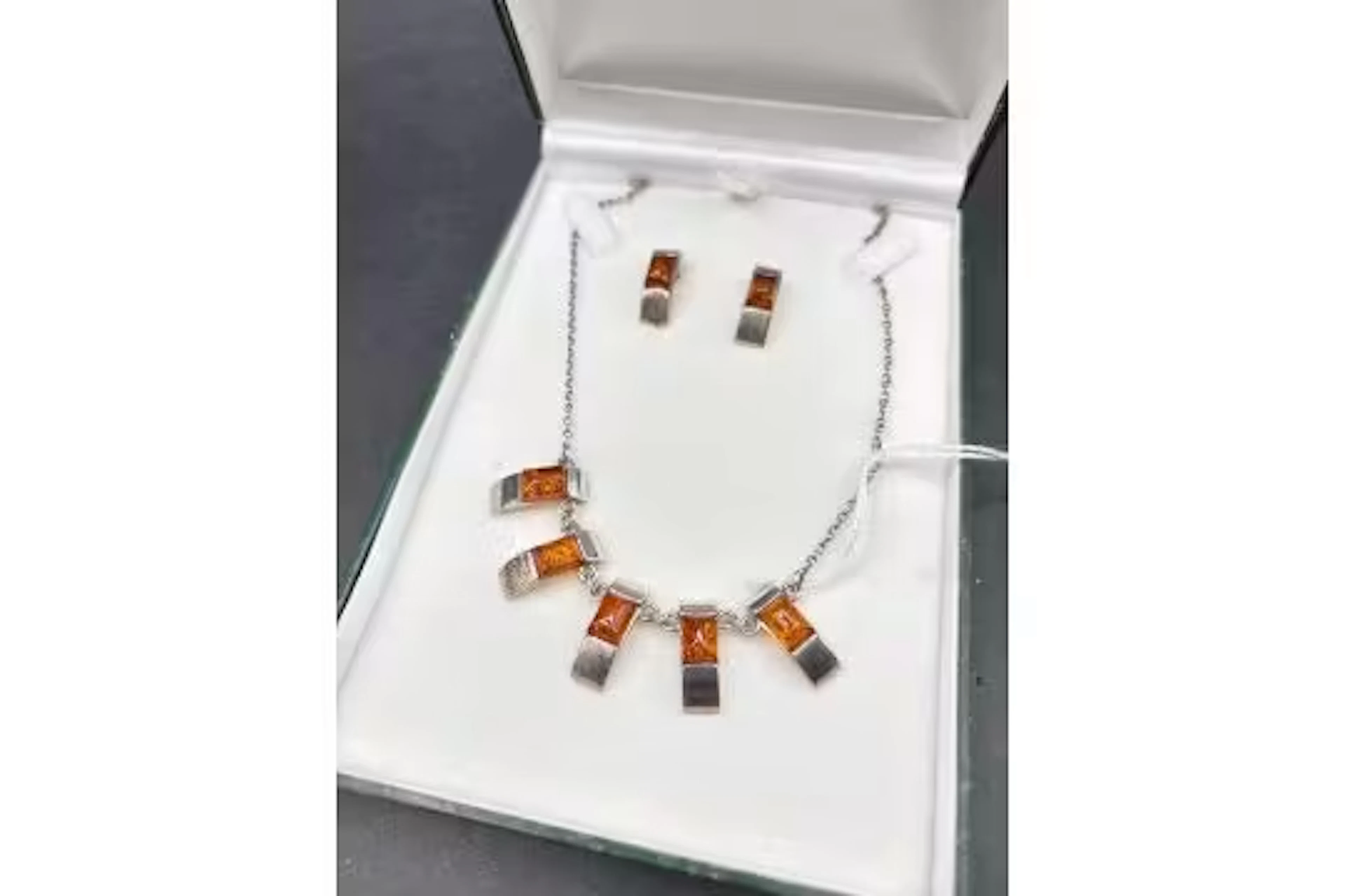 A silver and amber necklace and earrings in green boxed