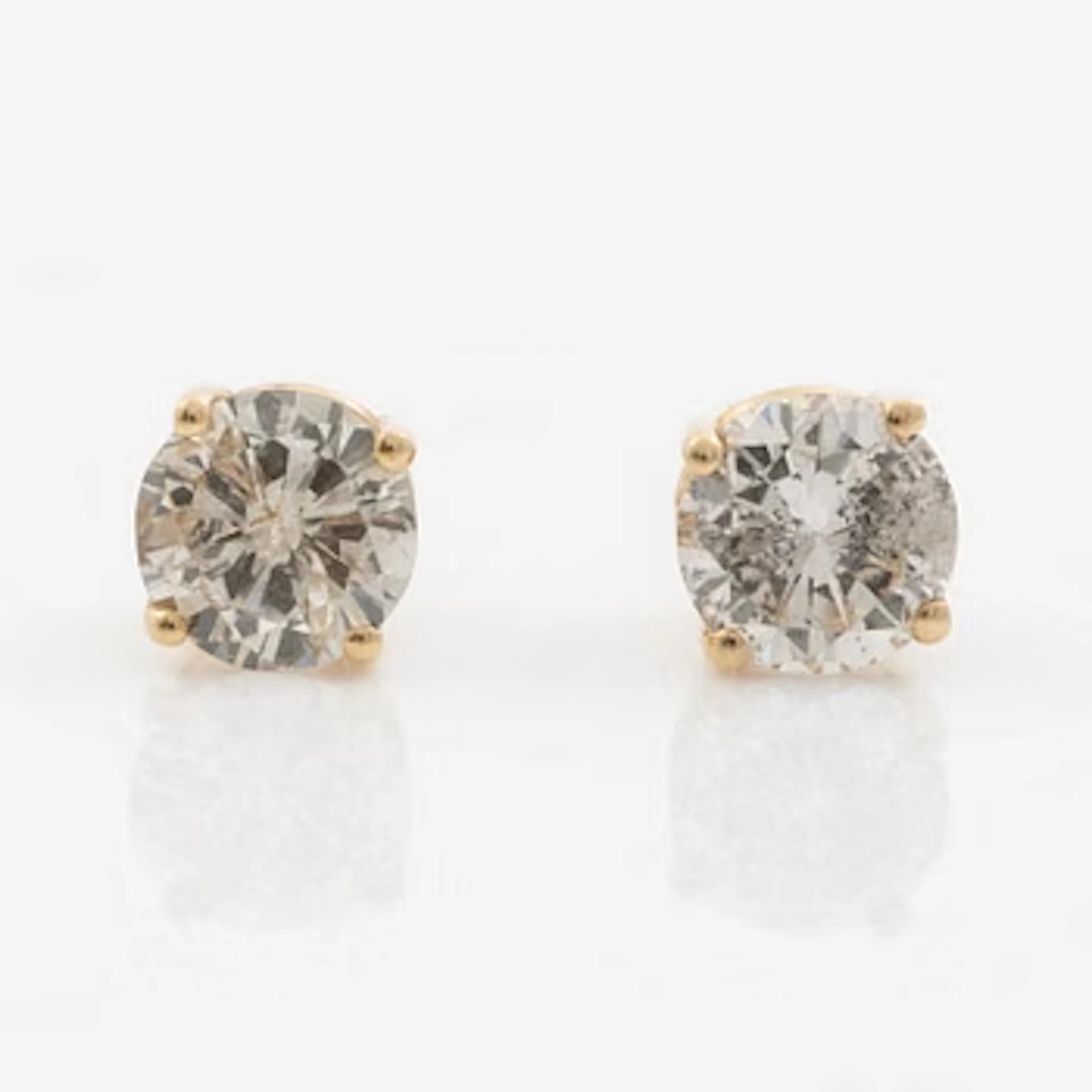 A pair of 14K gold earrings with round brilliant-cut diamonds.