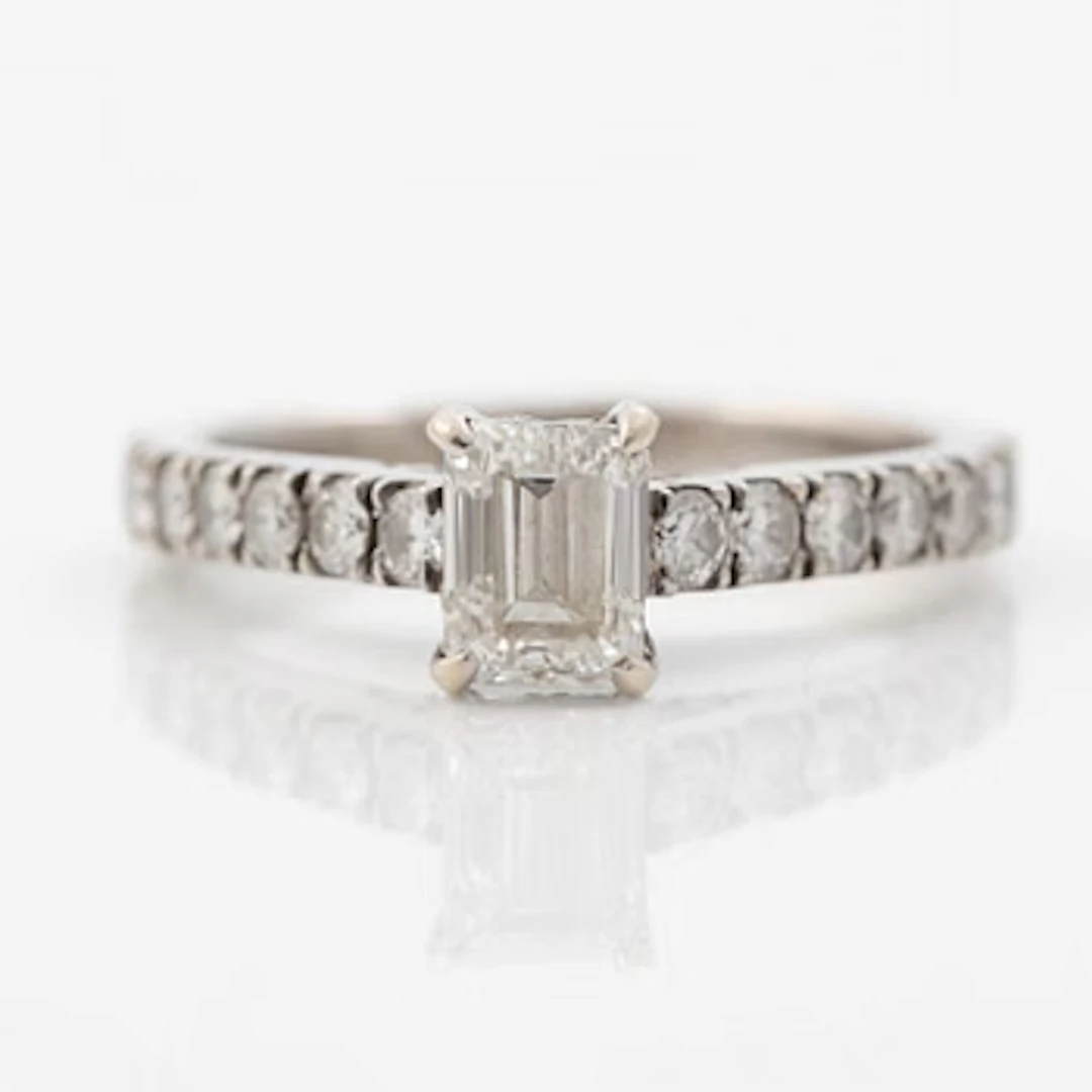 18K white gold ring set with an emerald-cut diamond and round brilliant-cut