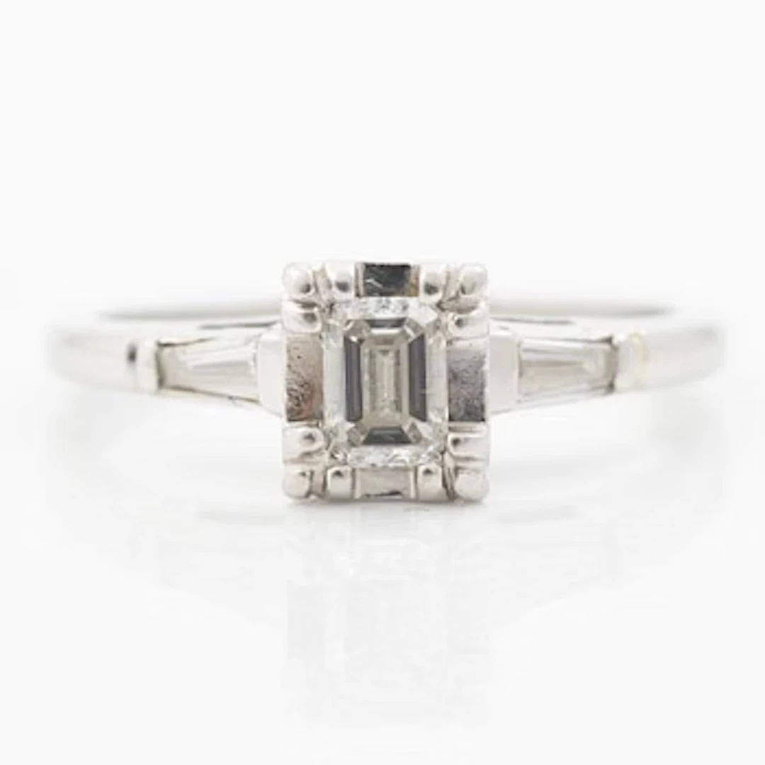 Platinum ring with an emerald-cut diamond and modified baguette-cut diamonds.