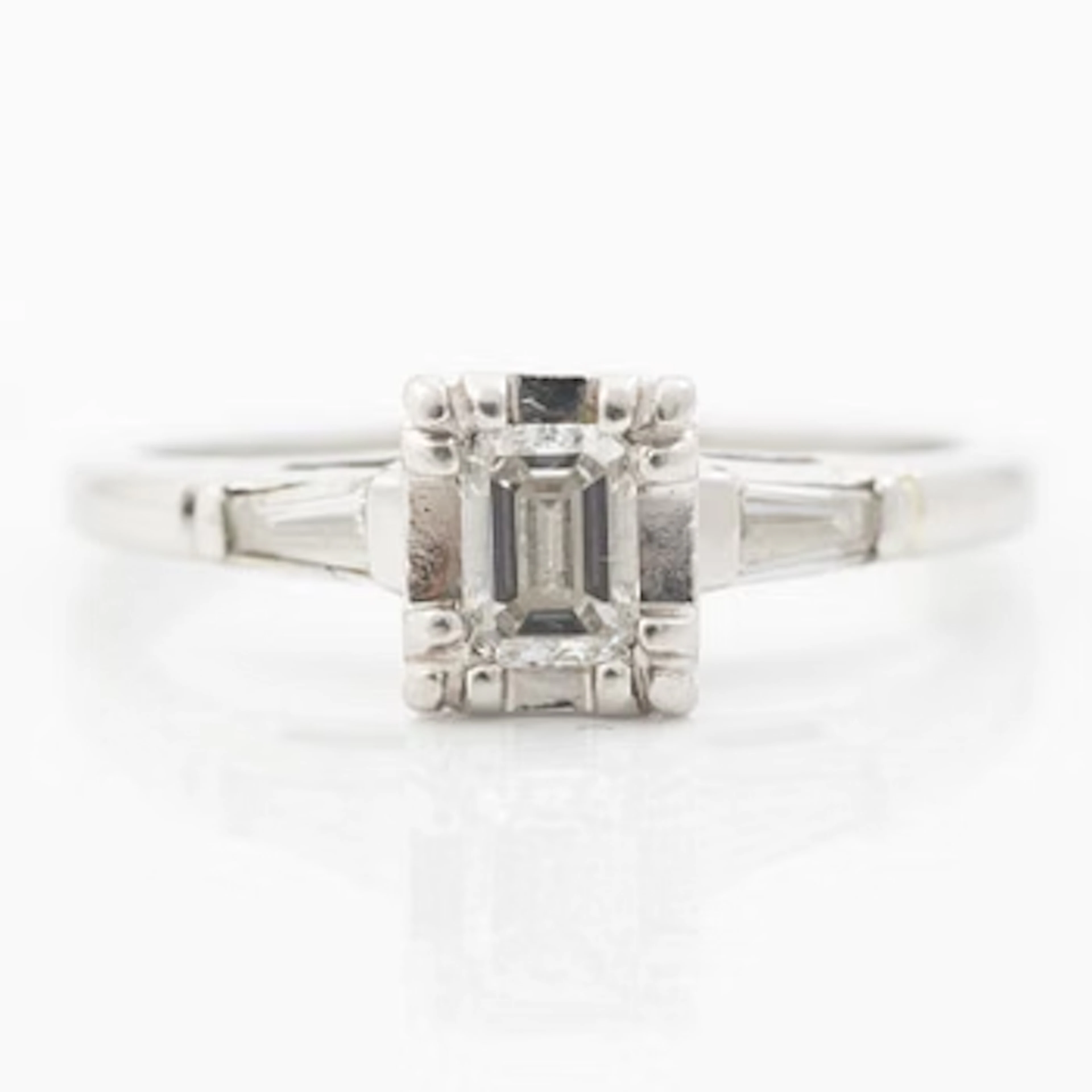 Platinum ring with an emerald-cut diamond and modified baguette-cut diamonds.