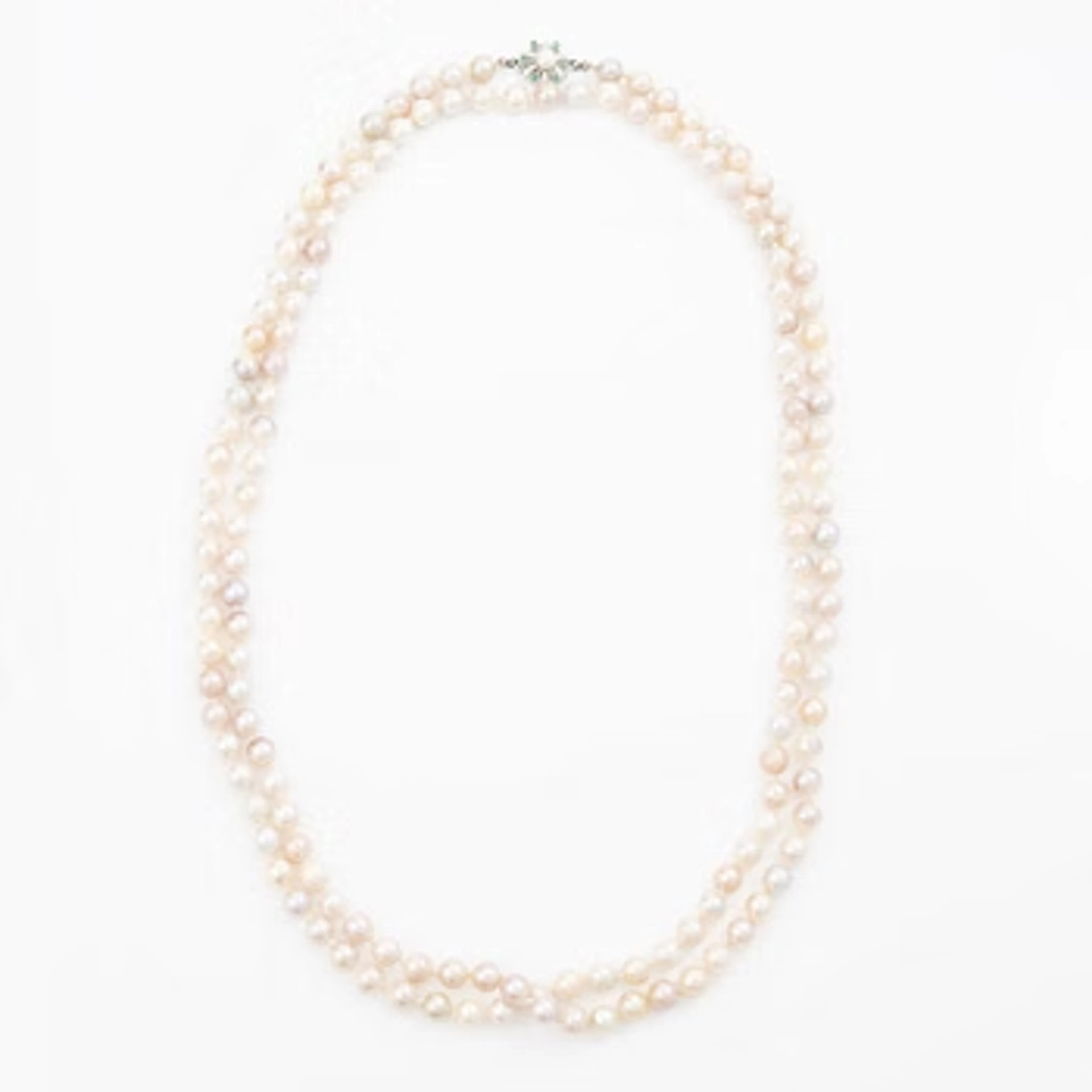 Long cultured pearl necklace with an 18K white gold clasp set with emeralds.