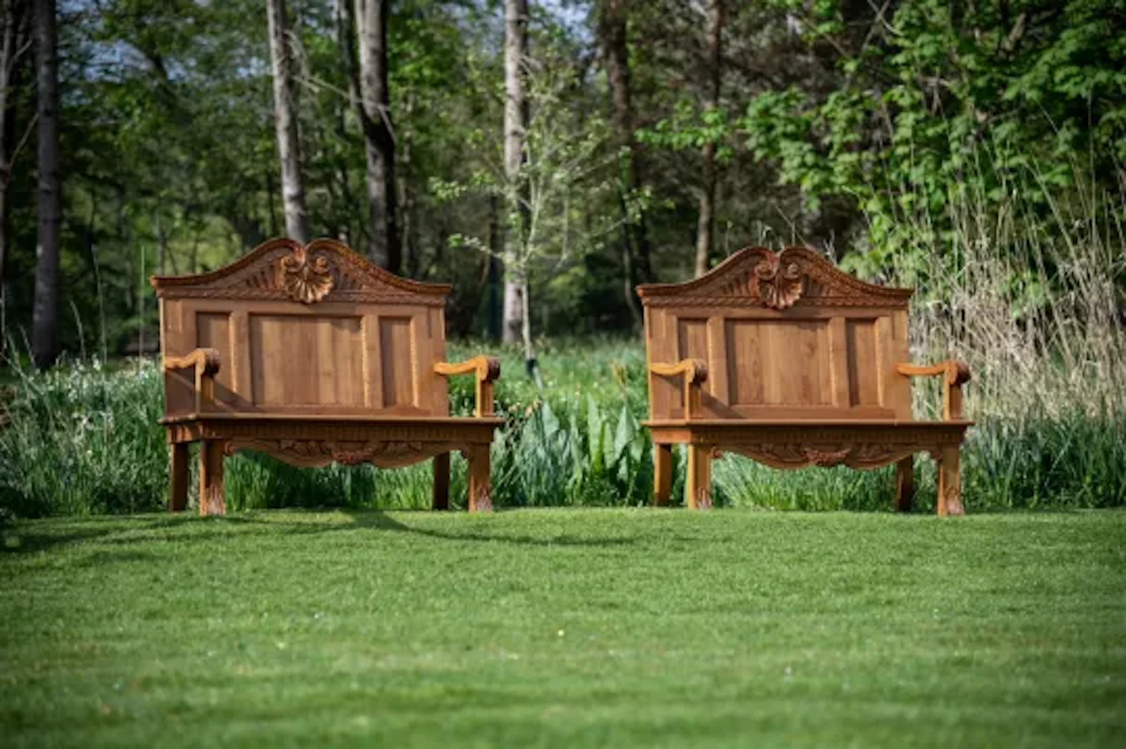 A PAIR OF CARVED TEAK GARDEN BENCHES, IN THE MANNER OF WILLIAM KENT