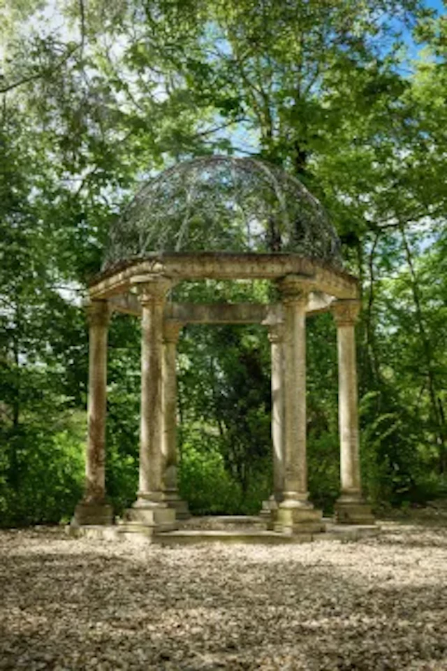 A LARGE WROUGHT IRON MOUNTED COMPOSITION STONE FOLLY OF CLASSICAL