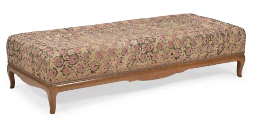 A WALNUT AND SUZANI FABRIC COVERED OTTOMAN, FRENCH, SUPPLIED BY ROBERT KIME