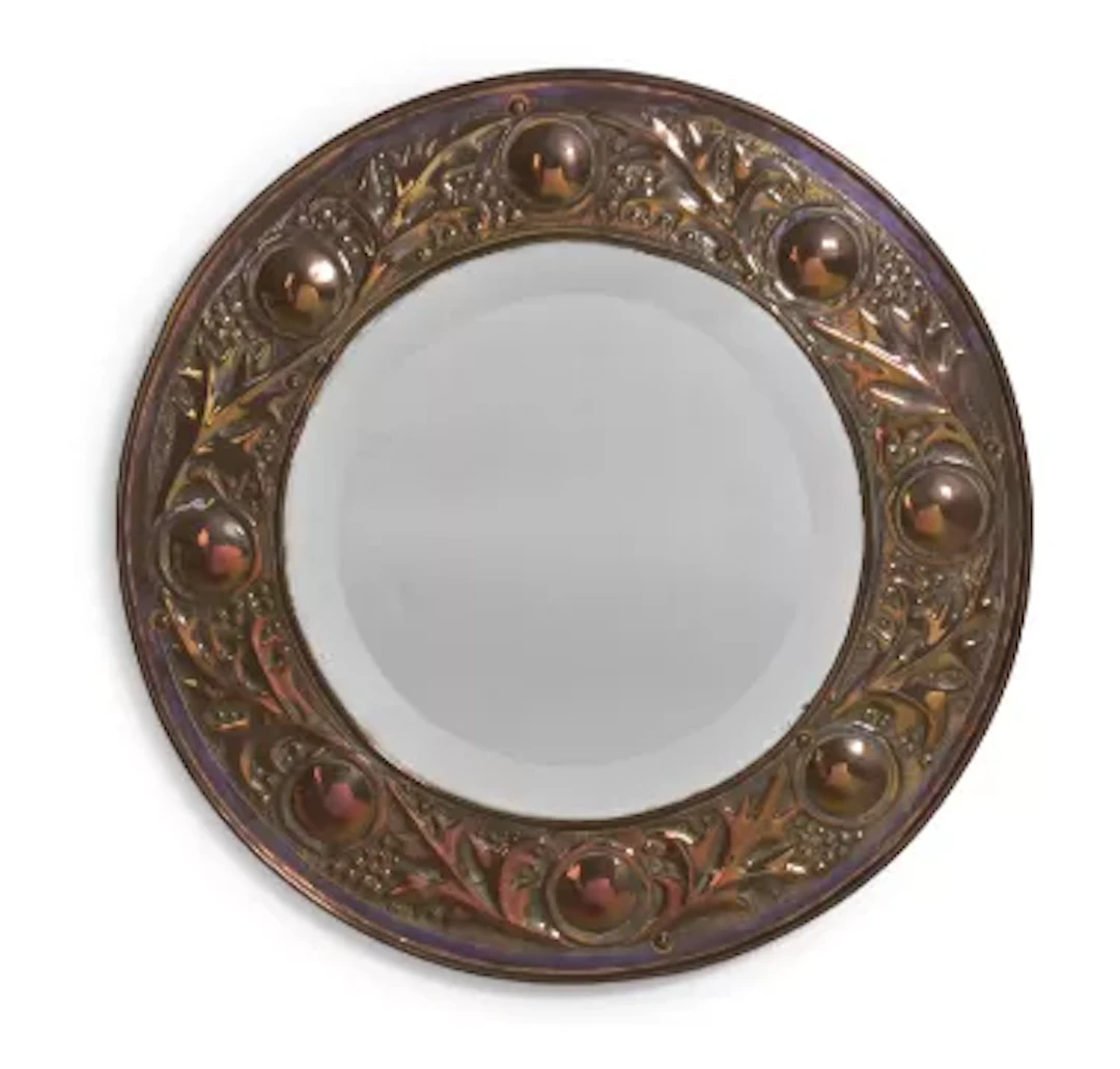 AN ARTS & CRAFTS EMBOSSED CIRCULAR WALL MIRROR, CIRCA 1900