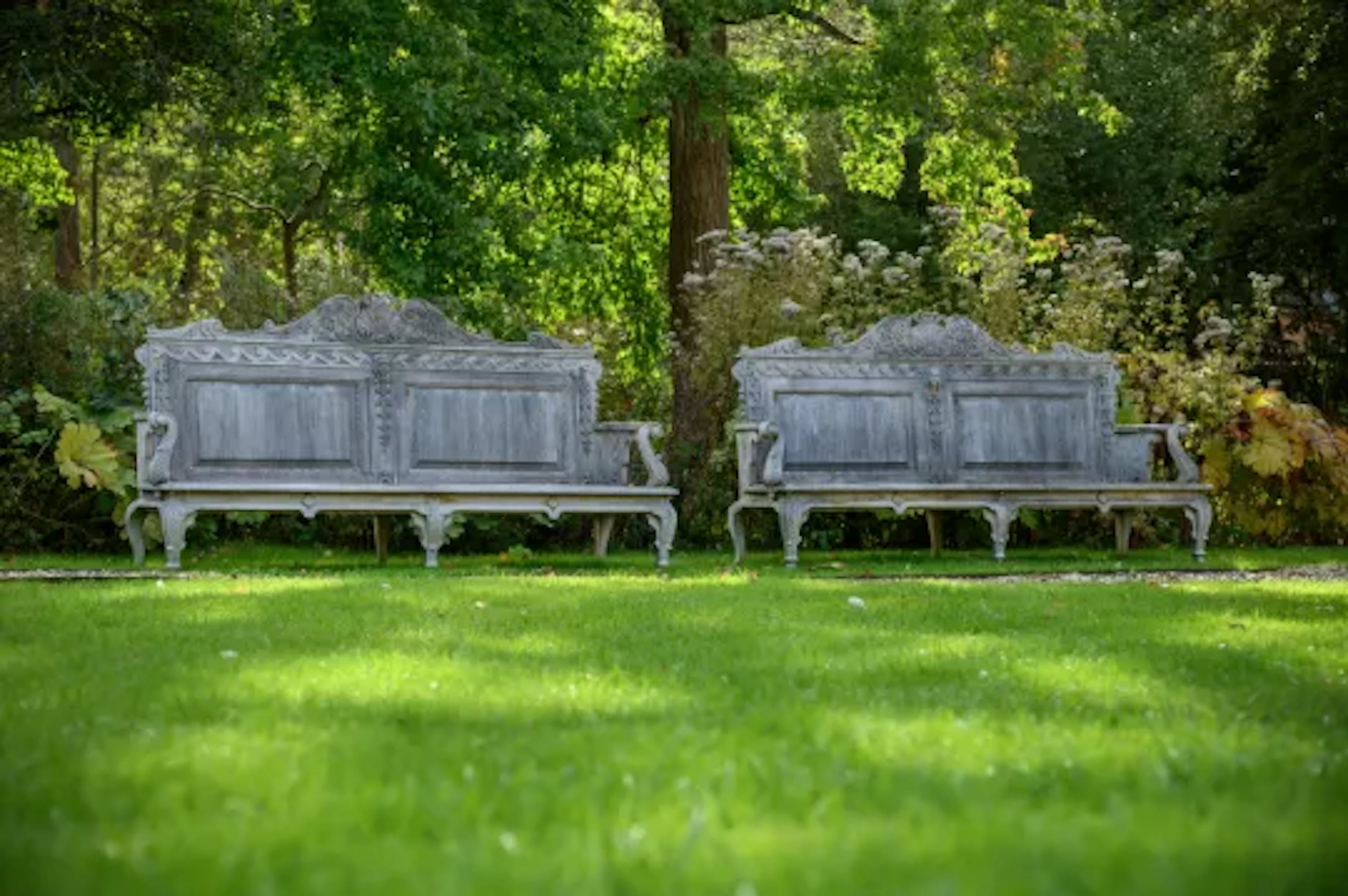 A LARGE PAIR OF CARVED TEAK GARDEN BENCHES, IN GEORGE II STYLE, CONTEMPORARY