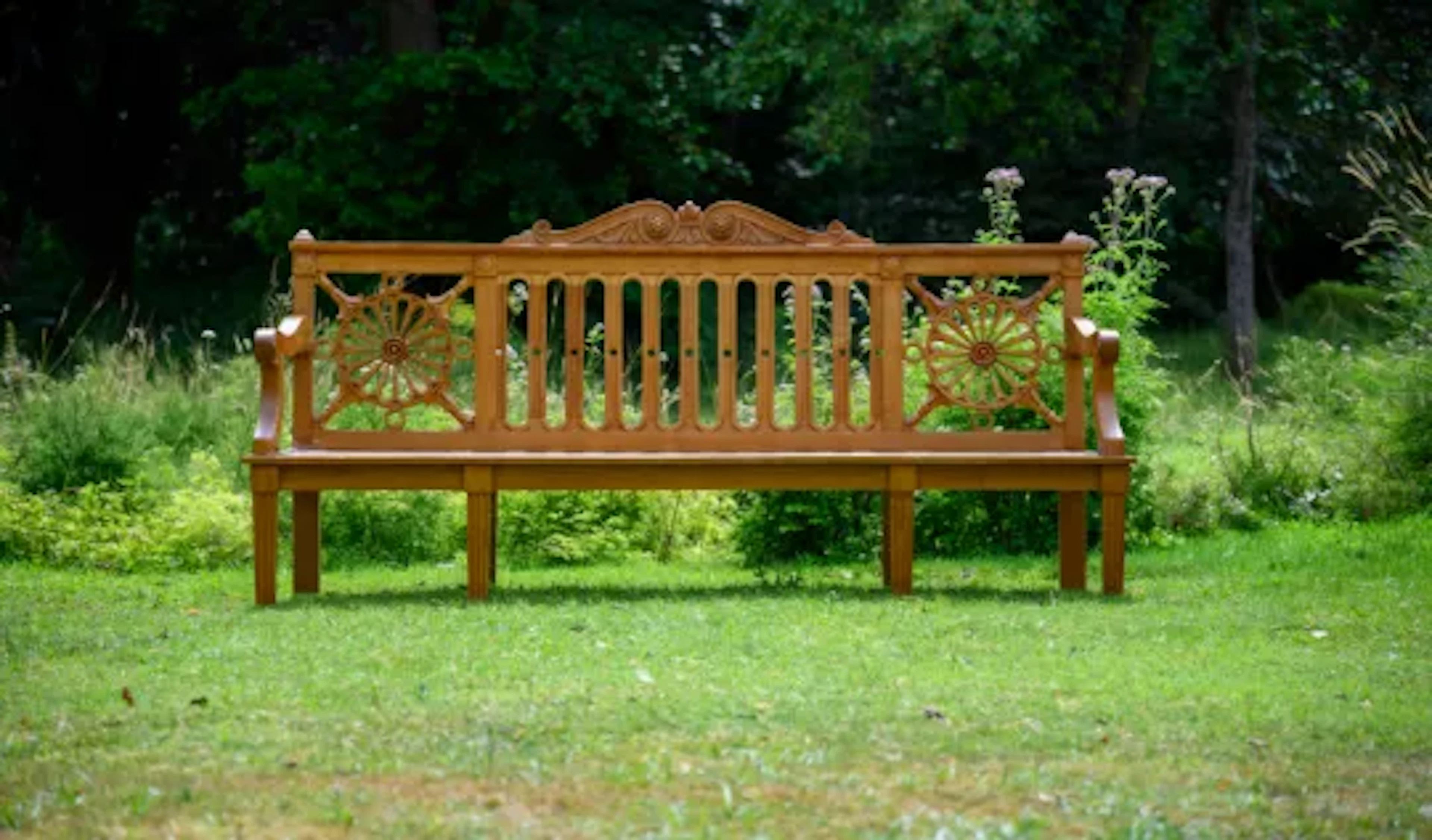 A CARVED TEAK 'HAREWOOD' GARDEN BENCH, IN THE MANNER OF THOMAS CHIPPENDALE