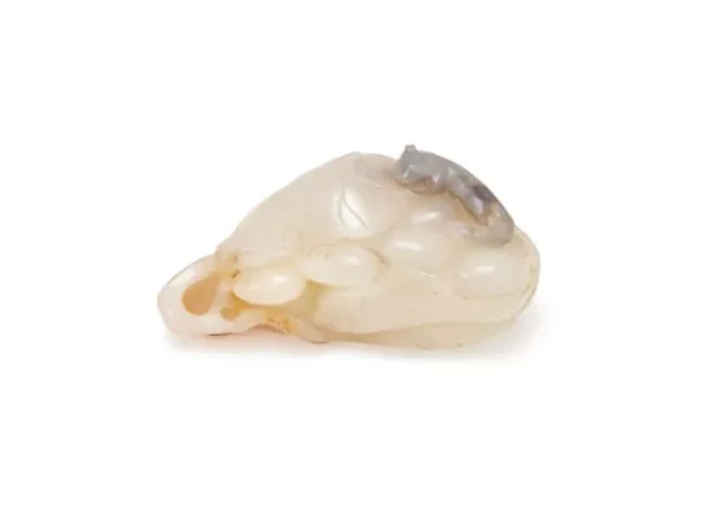 A Chinese white and russet jade 'Squirrel and grapes' pendant, Qing Dynasty