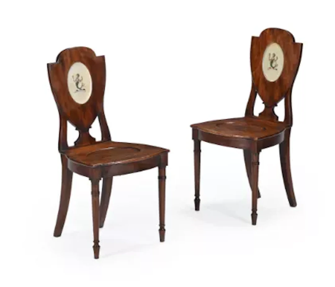 A PAIR OF GEORGE III MAHOGANY ARMORIAL HALL CHAIRS, CIRCA 1780