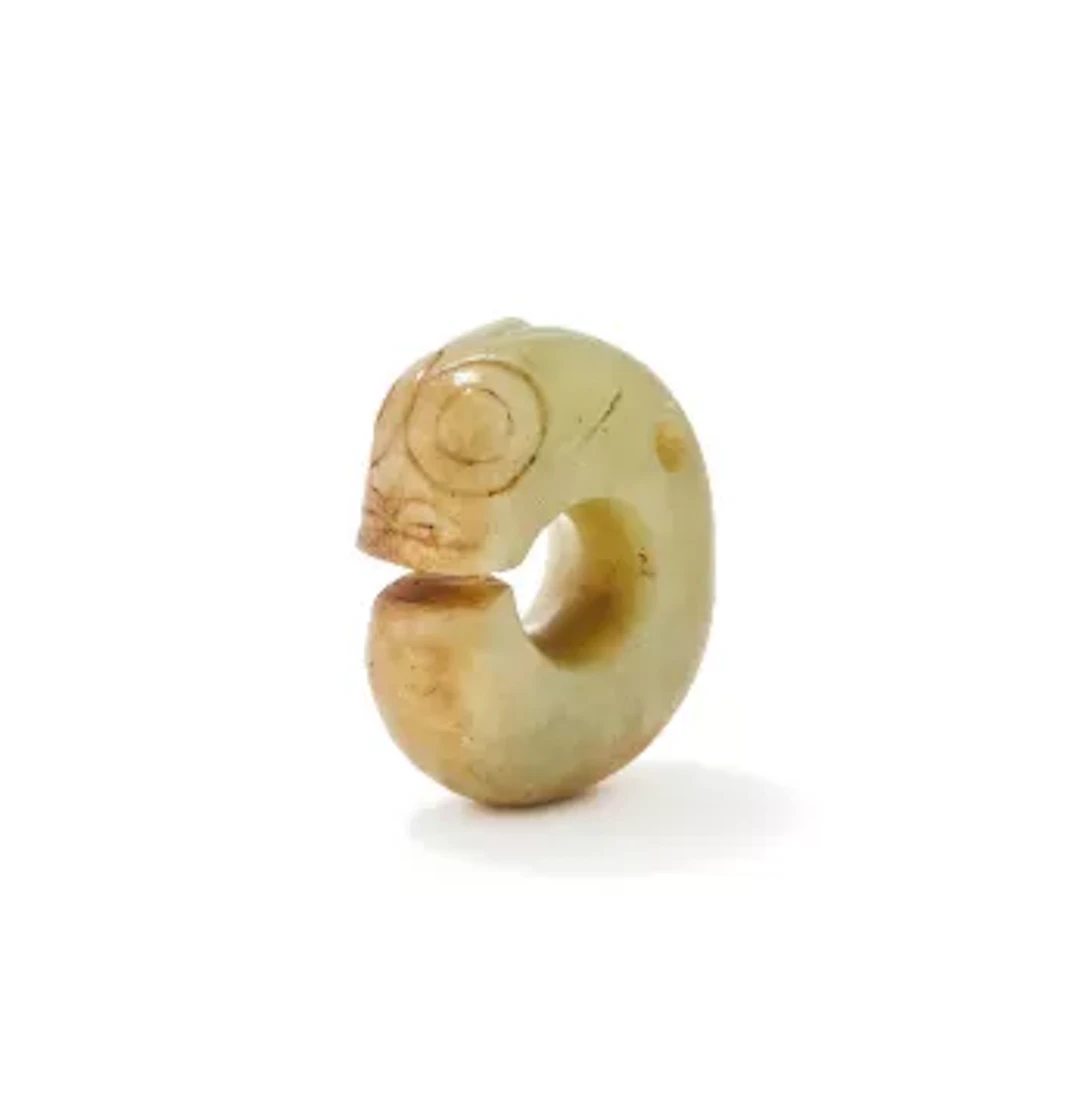 A Chinese celadon jade carving of a coiled stylised dragon, Ming Dynasty