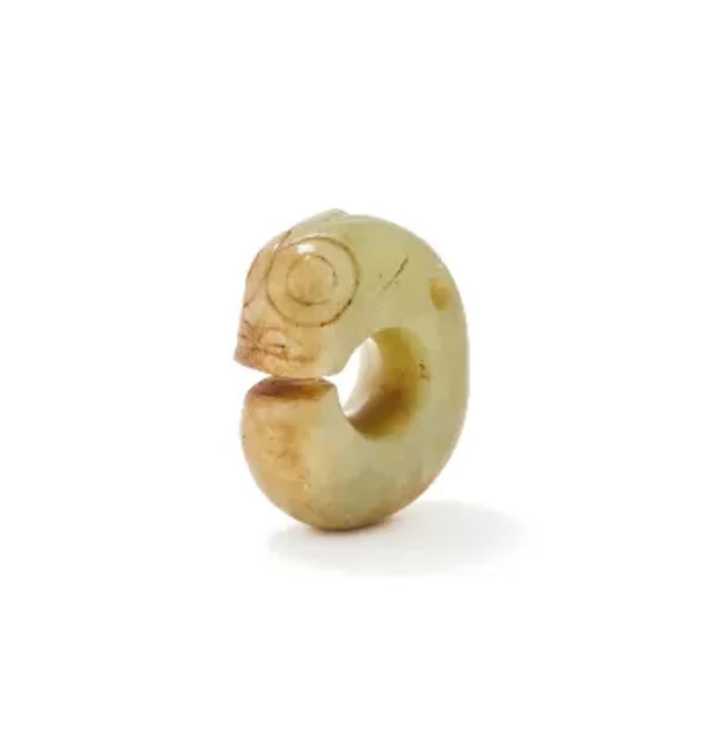 A Chinese celadon jade carving of a coiled stylised dragon, Ming Dynasty