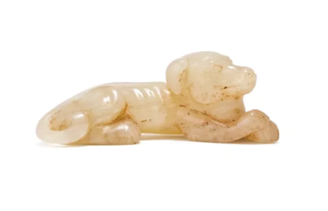 A Chinese pale celadon jade carving of a recumbent dog, Song Dynasty