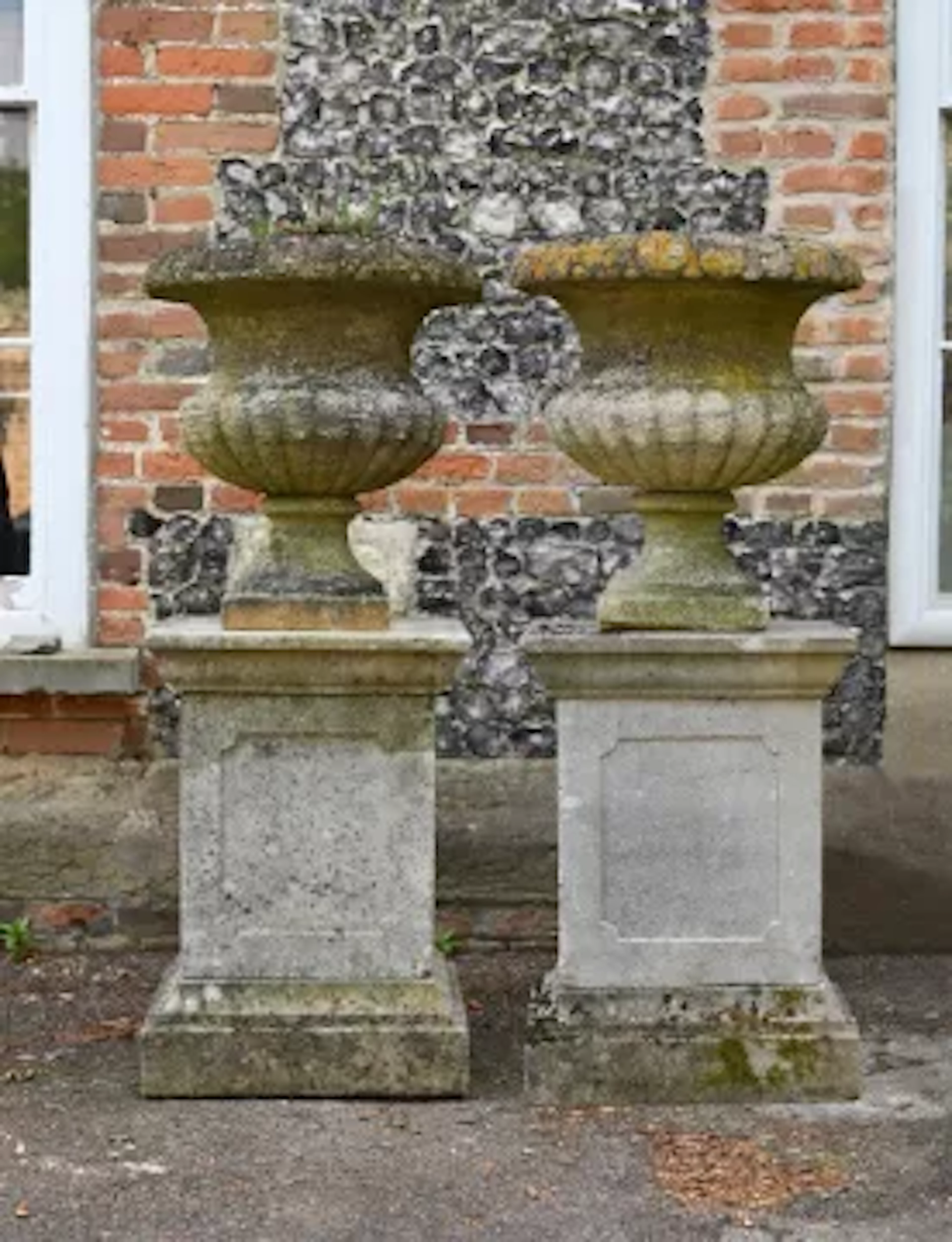 A PAIR OF GEORGE III CARVED COTSWOLD STONE URN PLANTERS, CIRCA 1800