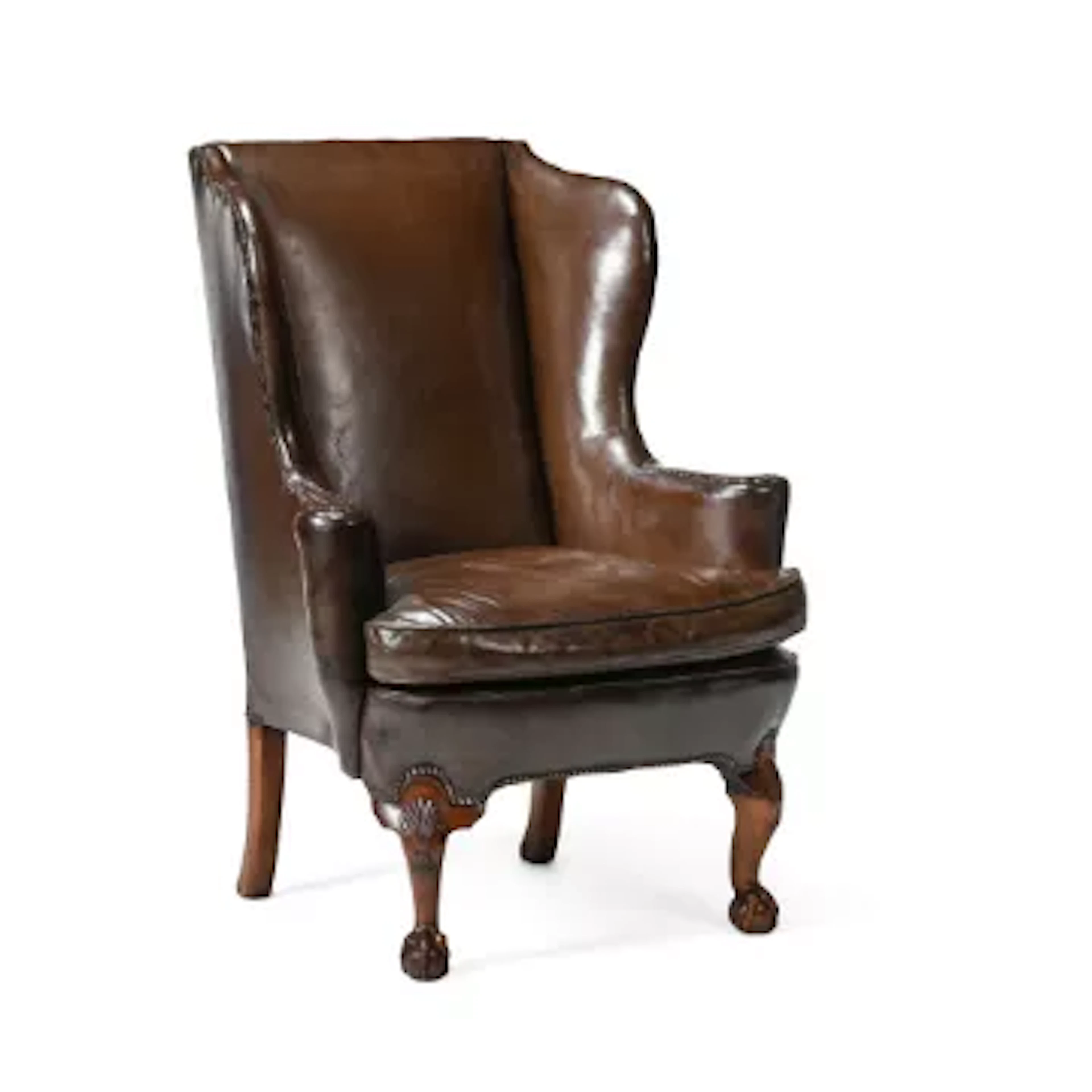 A CARVED WALNUT AND LEATHER UPHOLSTERED WING ARMCHAIR, BY HOWARD &