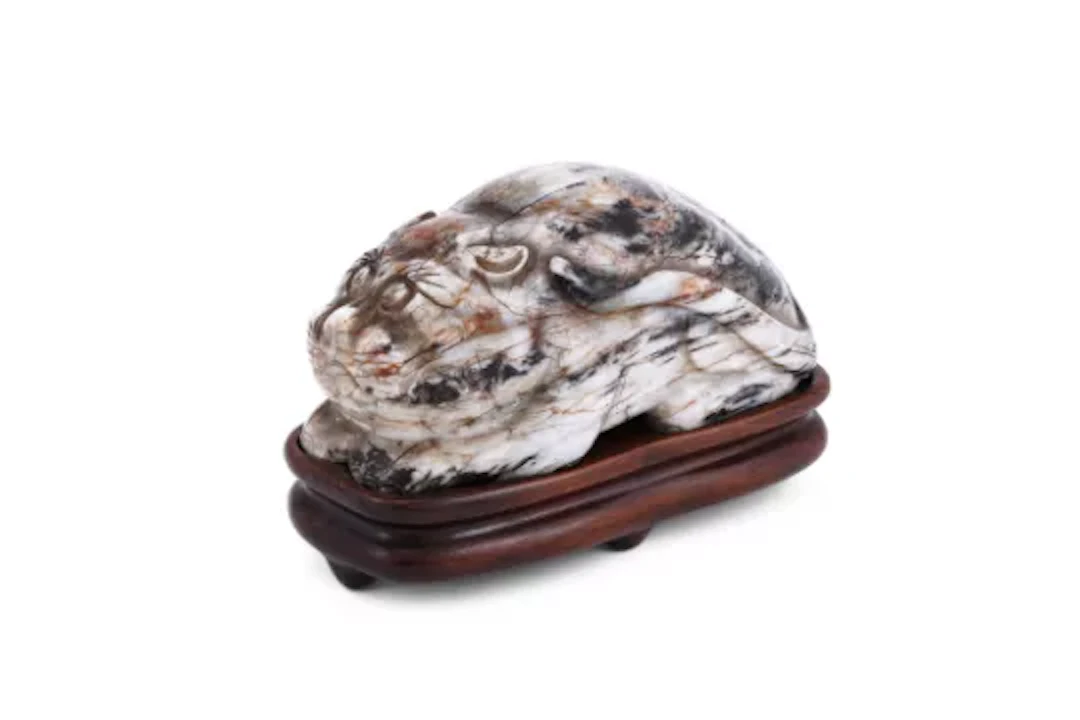 A Chinese mottled grey and russet jade model of a cat, Ming Dynasty