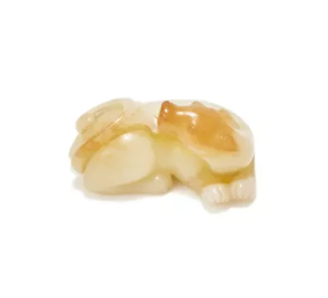 A Chinese white and russet jade carving of a recumbent beast, Qing Dynasty