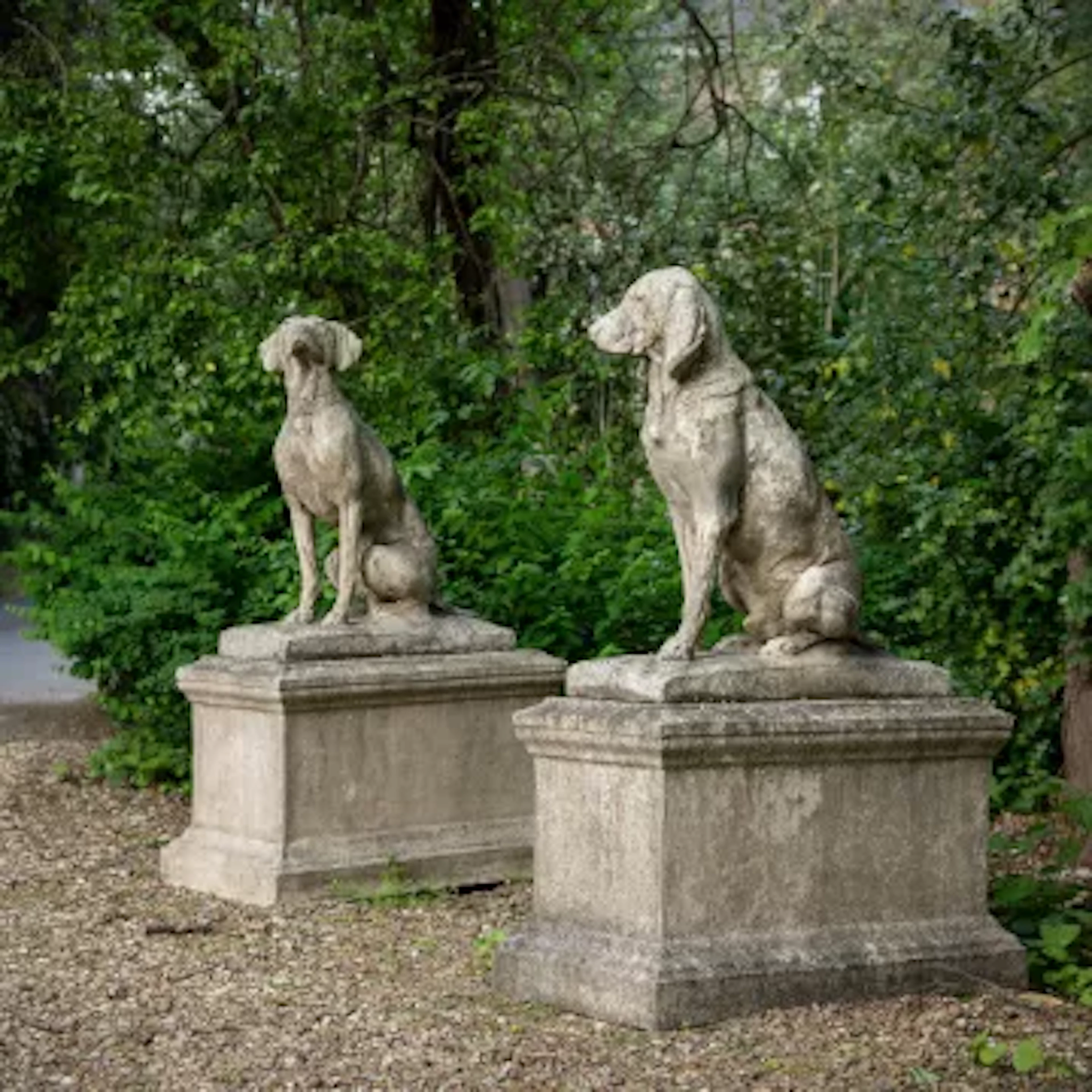 A PAIR OF STONE COMPOSITION MODELS OF SEATED HOUNDS ON PLINTHS, 20TH CENTURY